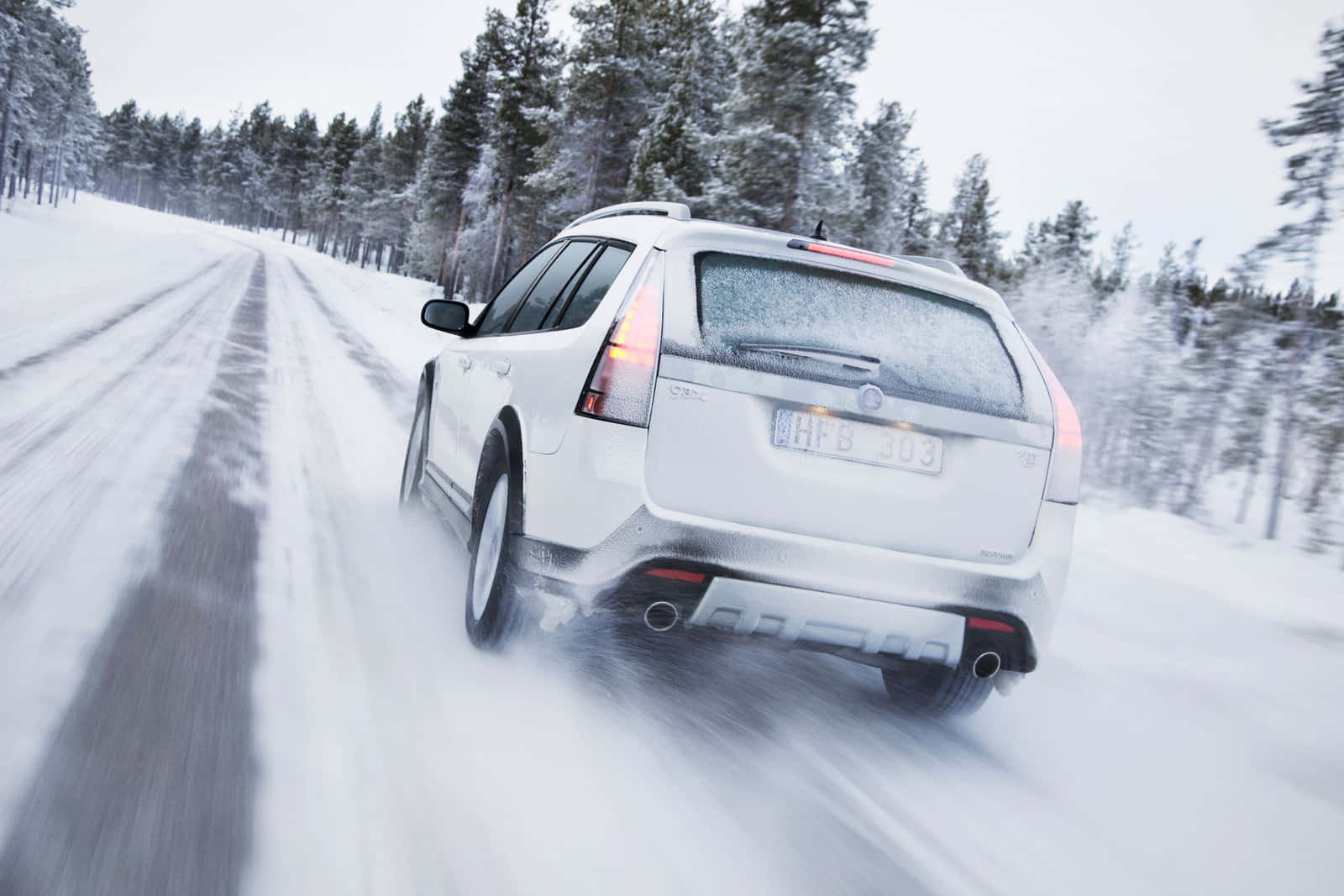 Une Route Hivernale Enneigée Avec Une Voiture Traversant Le Paysage Pittoresque Fond d'écran