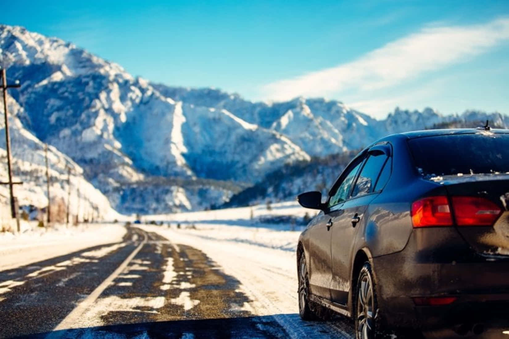 Car driving through snowy winter landscape Wallpaper