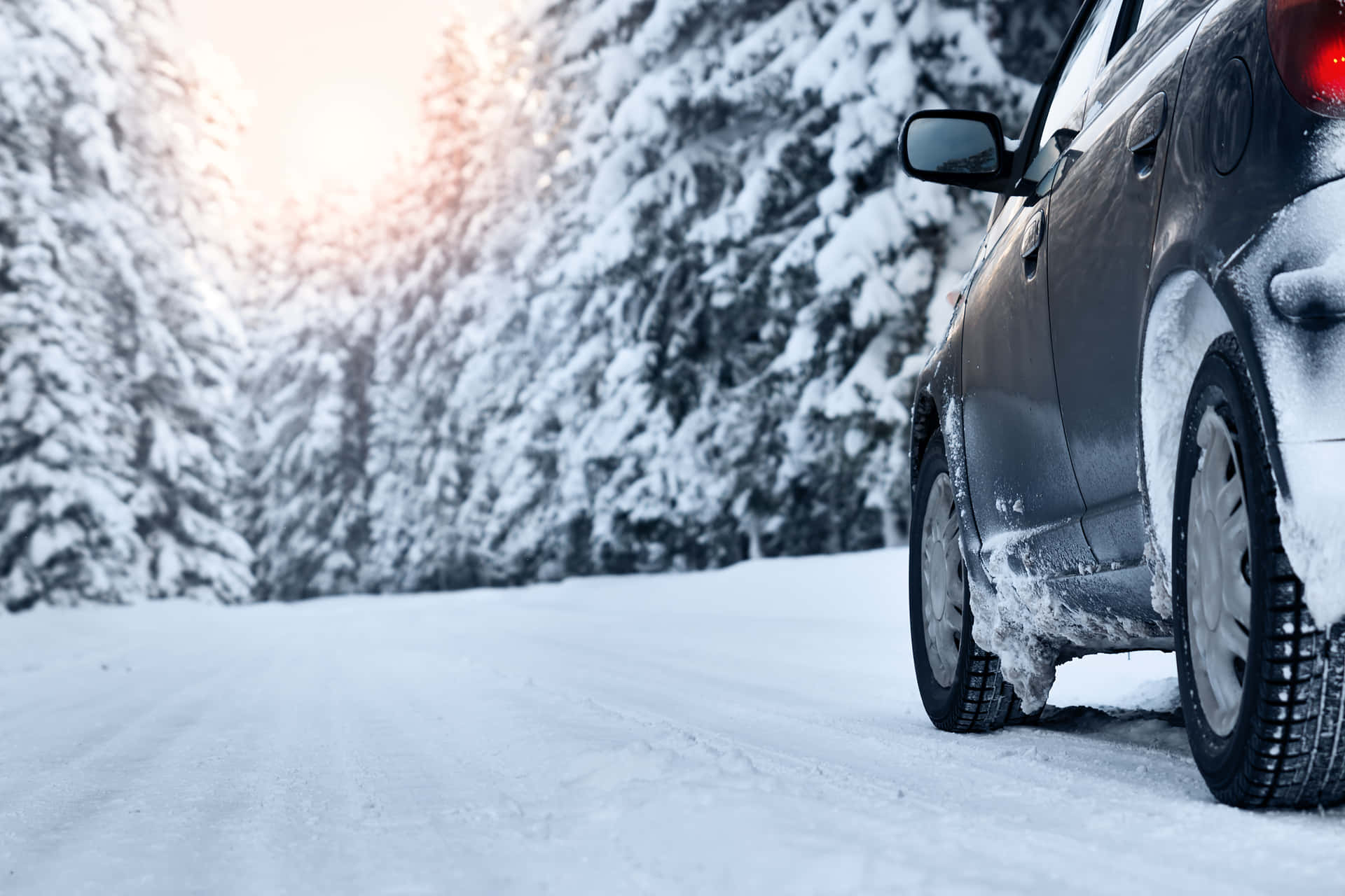 Snowy winter road with a vehicle driving in challenging conditions Wallpaper