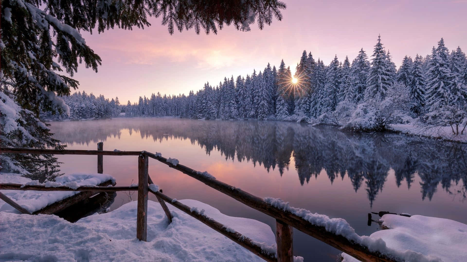 A Lake With Snow Covered Trees And A Bridge Wallpaper