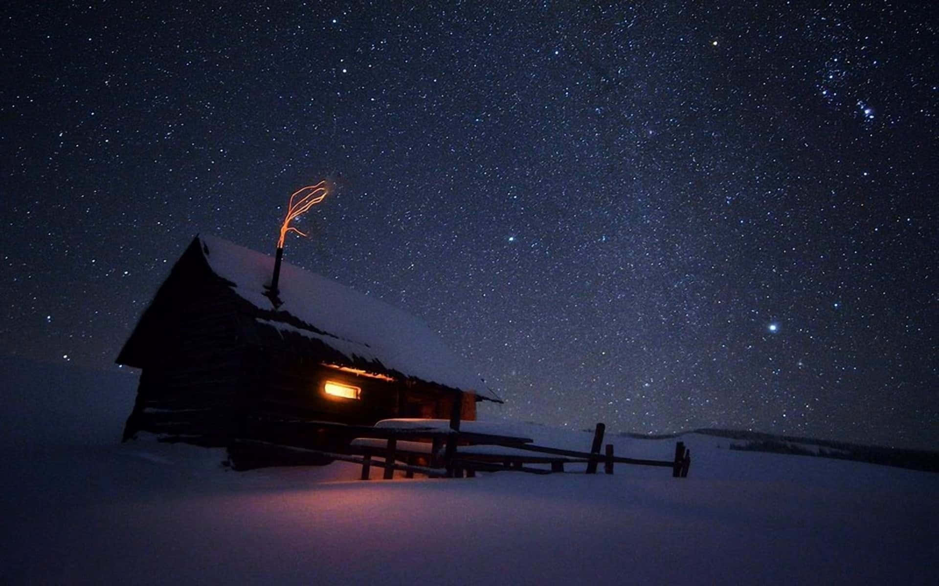 A Small Cabin Under The Stars In The Snow Wallpaper