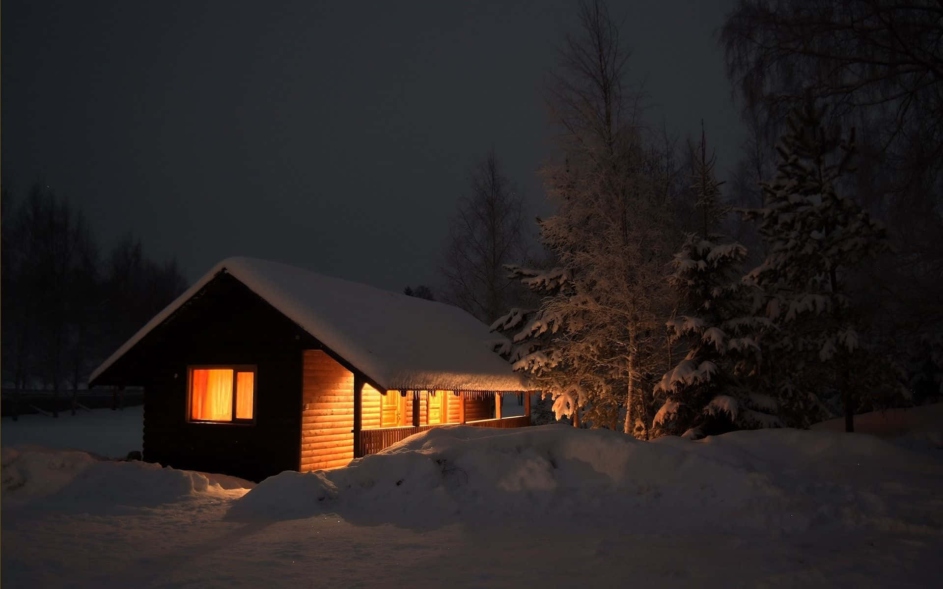 Umapequena Cabana Iluminada À Noite Na Neve. Papel de Parede