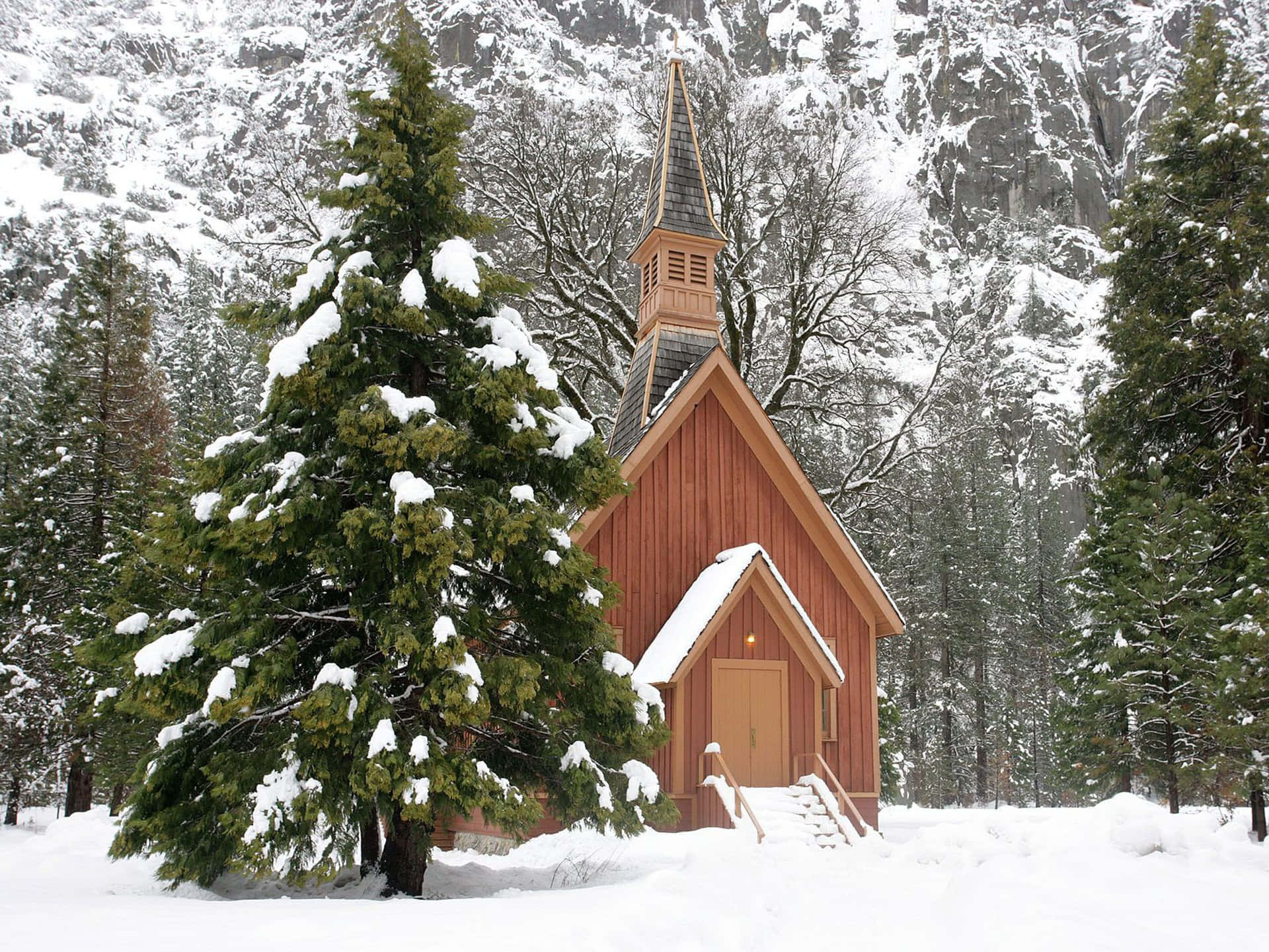 A Small Church In The Snow With Trees Surrounding It