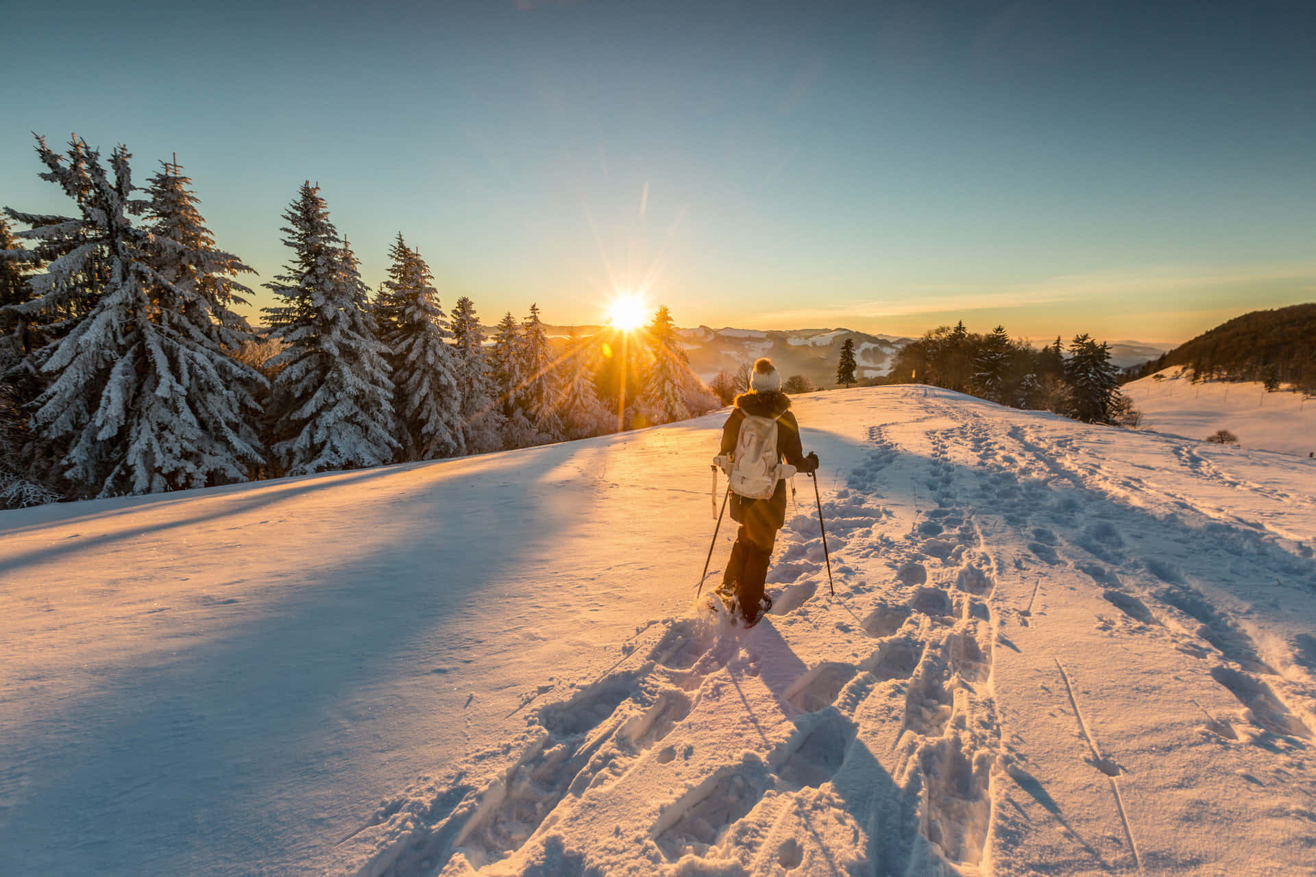 A Woman Is Skiing Down A Snowy Hill At Sunset