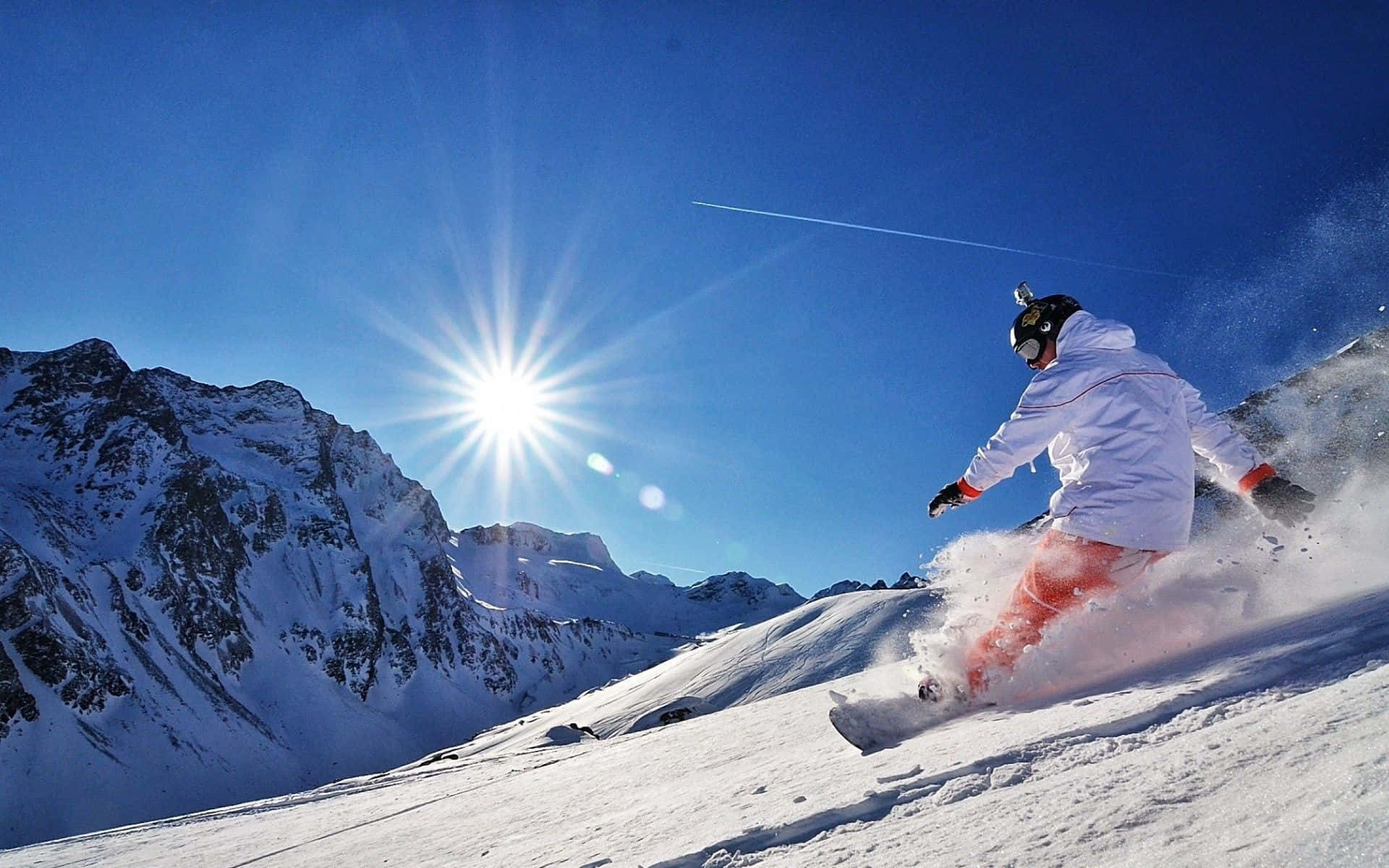 Snowboarder flying high over a snowy mountain Wallpaper