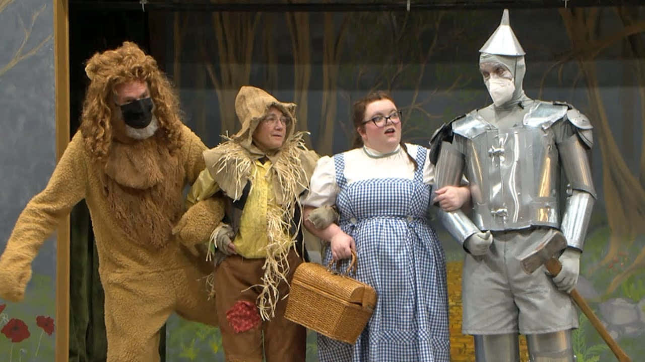 Dorothy, the Scarecrow, and the Tin Man venture down the yellow brick road in search of an adventure in The Wizard of Oz.