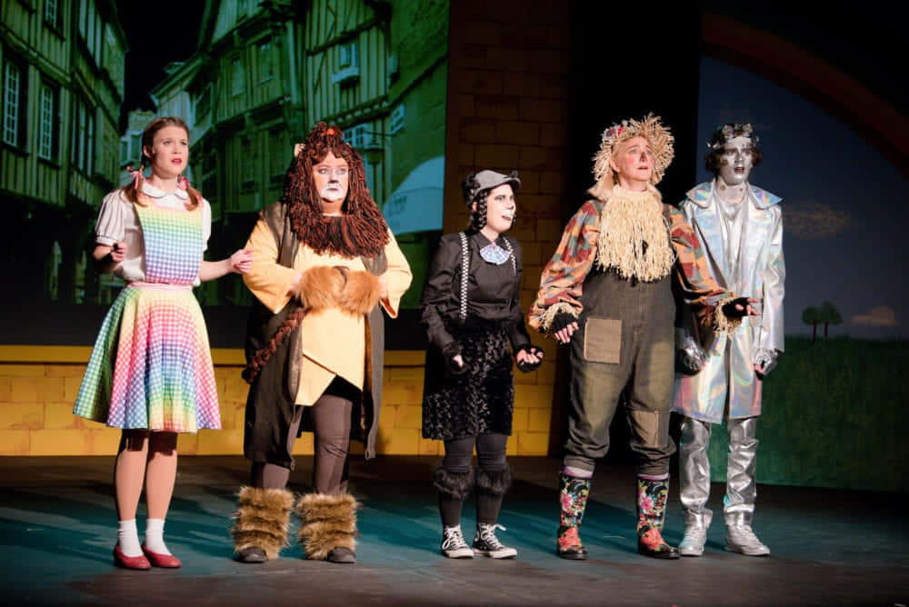 A Group Of People Dressed Up In Costumes On Stage