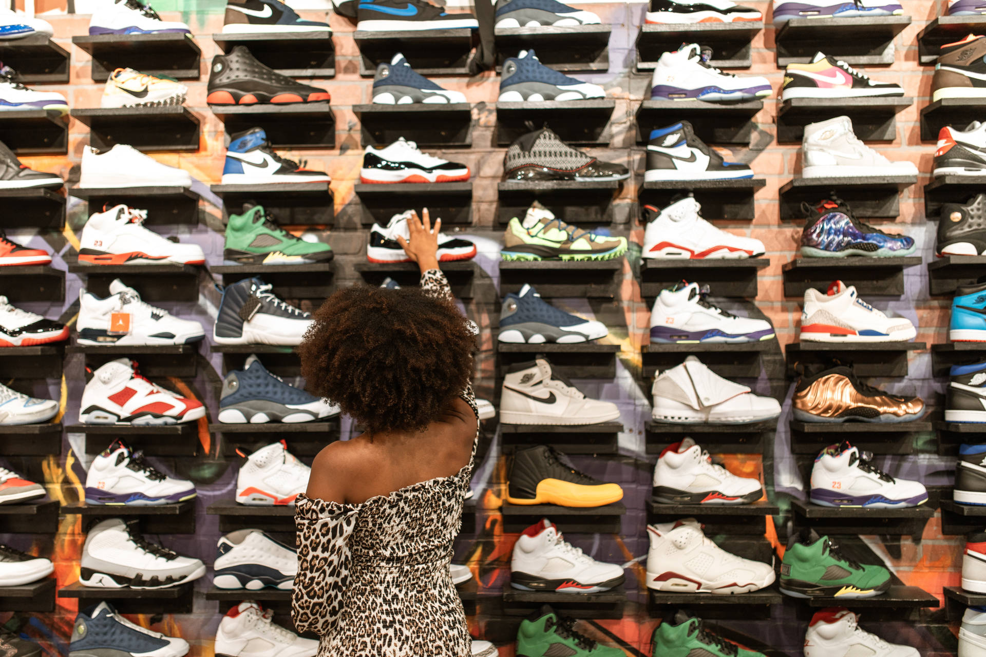 Stylish woman choosing footwear by shoe rack. Wallpaper