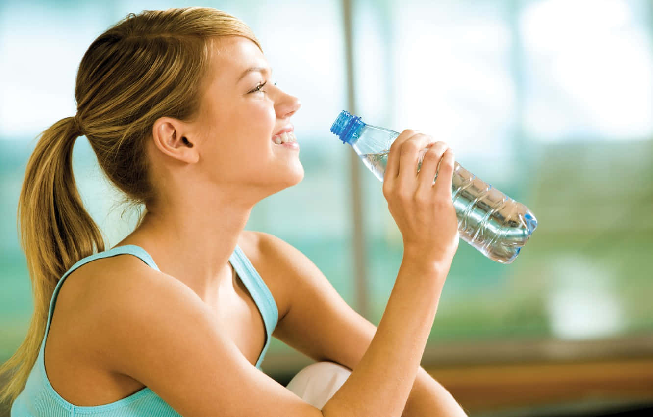 Health-conscious Woman Enjoying A Refreshing Drink Of Vital Water. Wallpaper