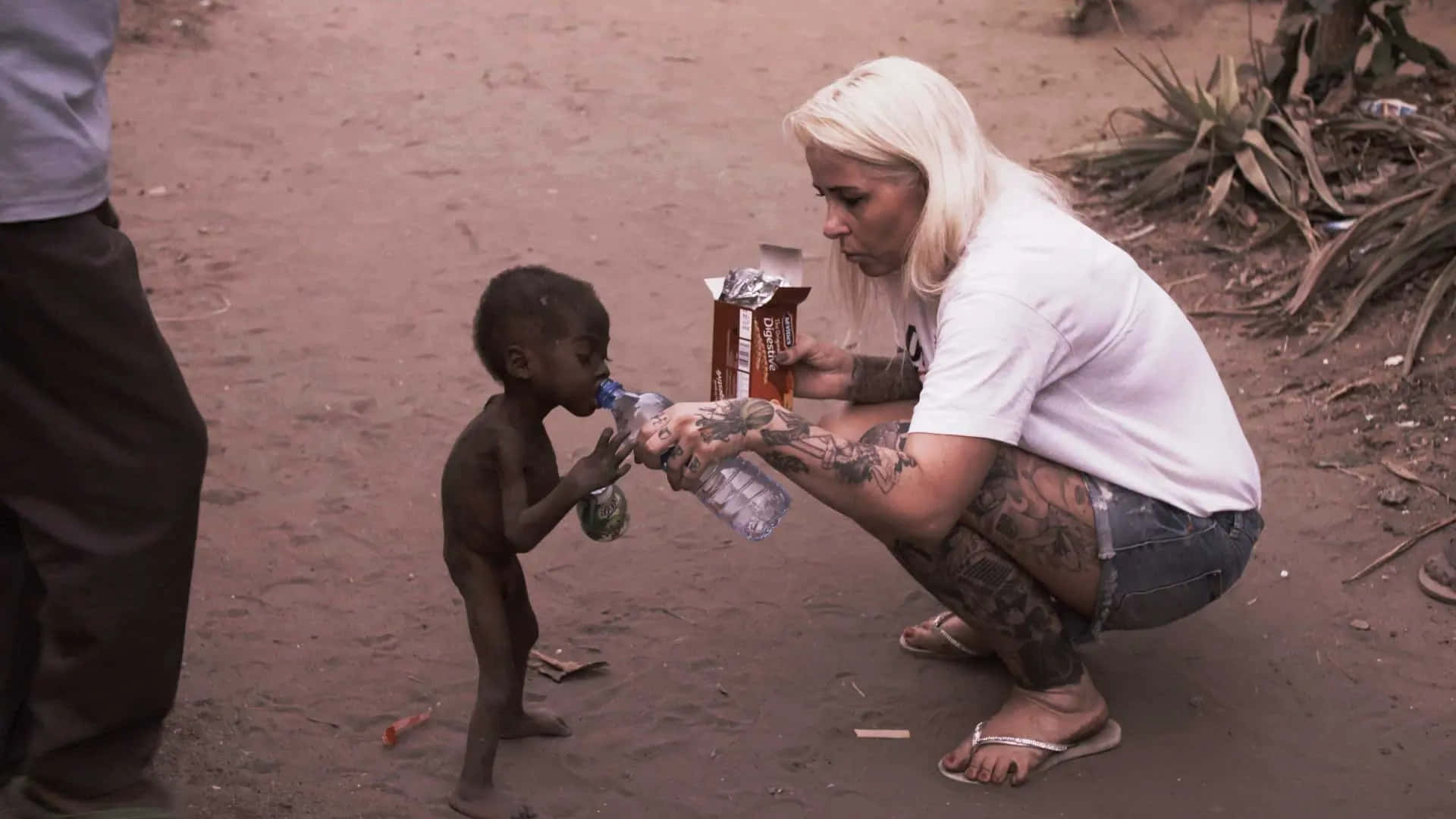 Woman Giving Water To An Emaciated Boy Wallpaper