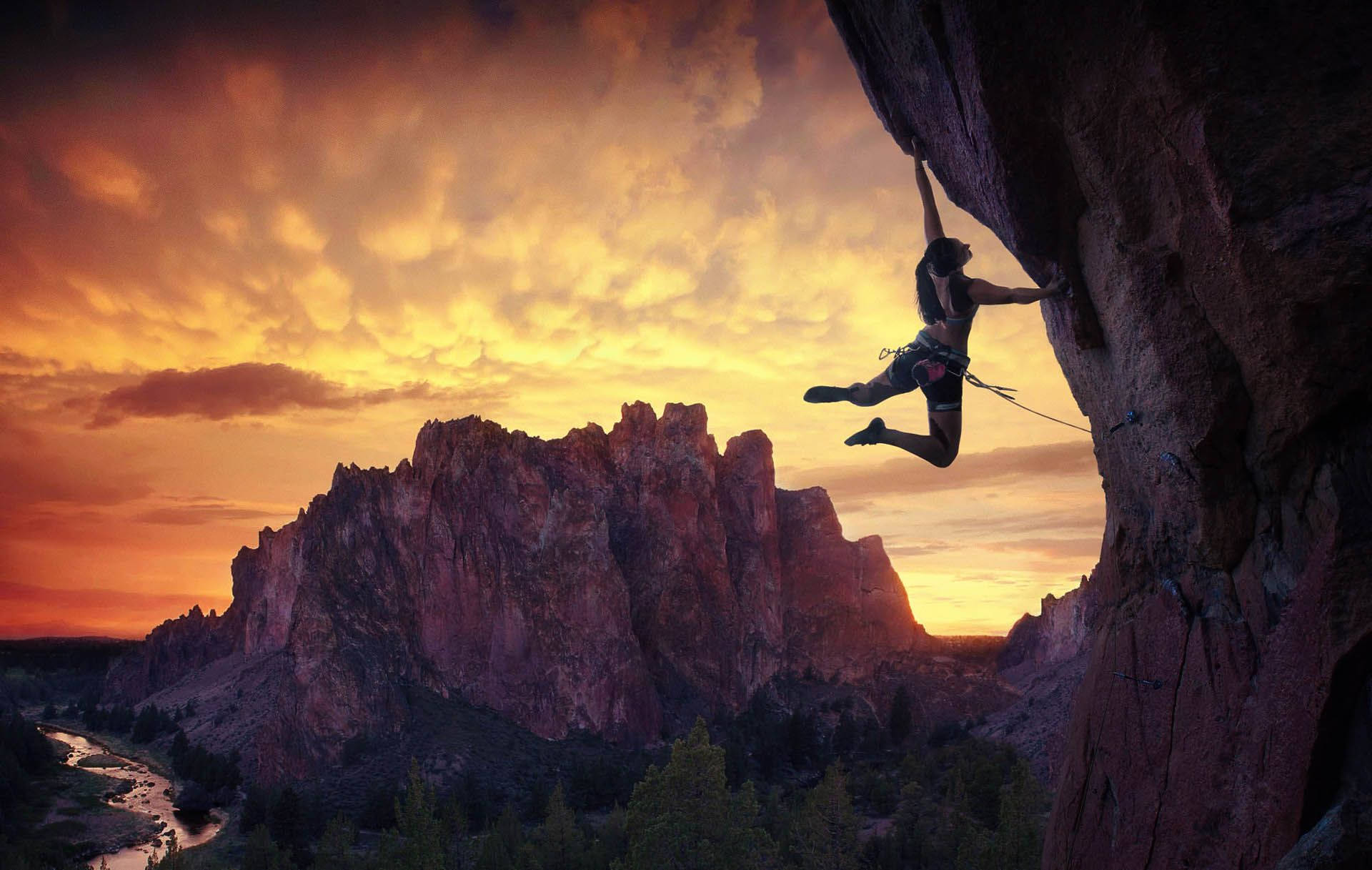Kvinde hænger og kravler på en bjerg sten ved siden af et sø Wallpaper