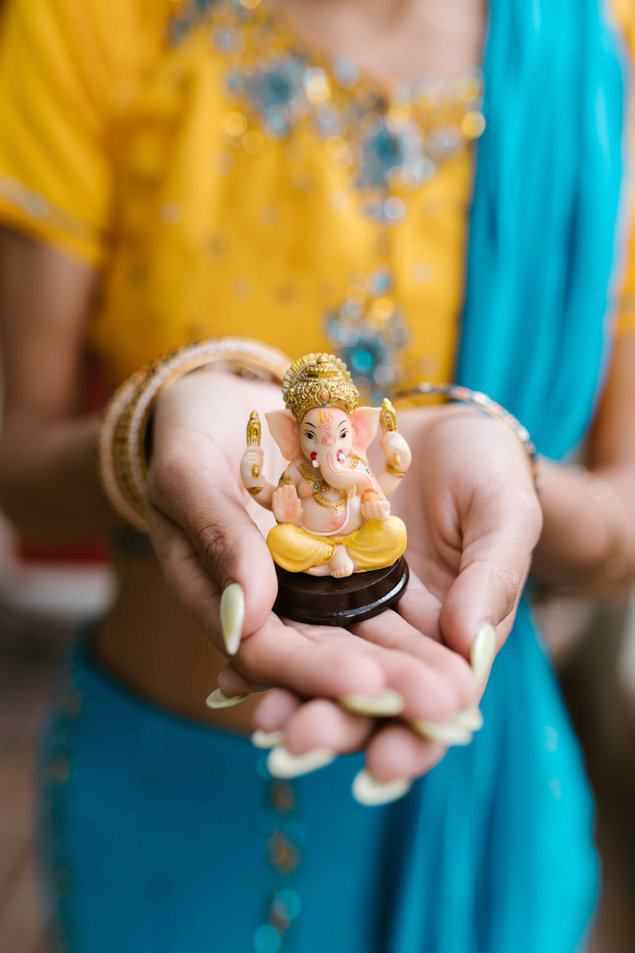 Mujersosteniendo Una Pequeña Estatua De Ganesh En 4k. Fondo de pantalla