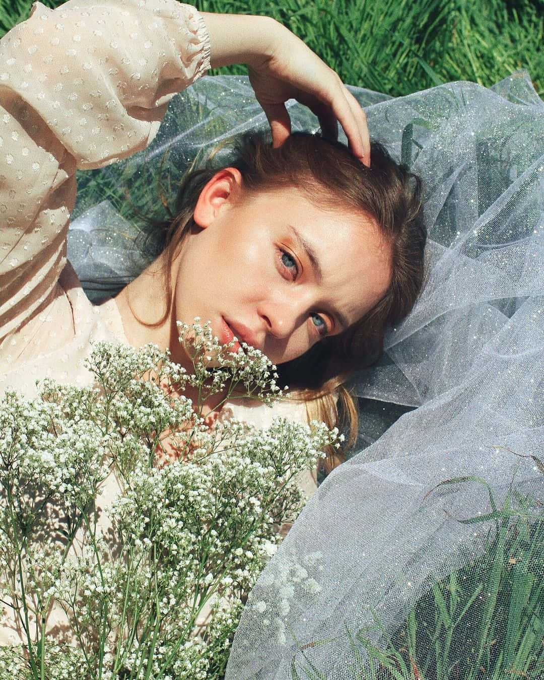 Vrouw Liggend In Gras Met Bloemen En Tule Achtergrond