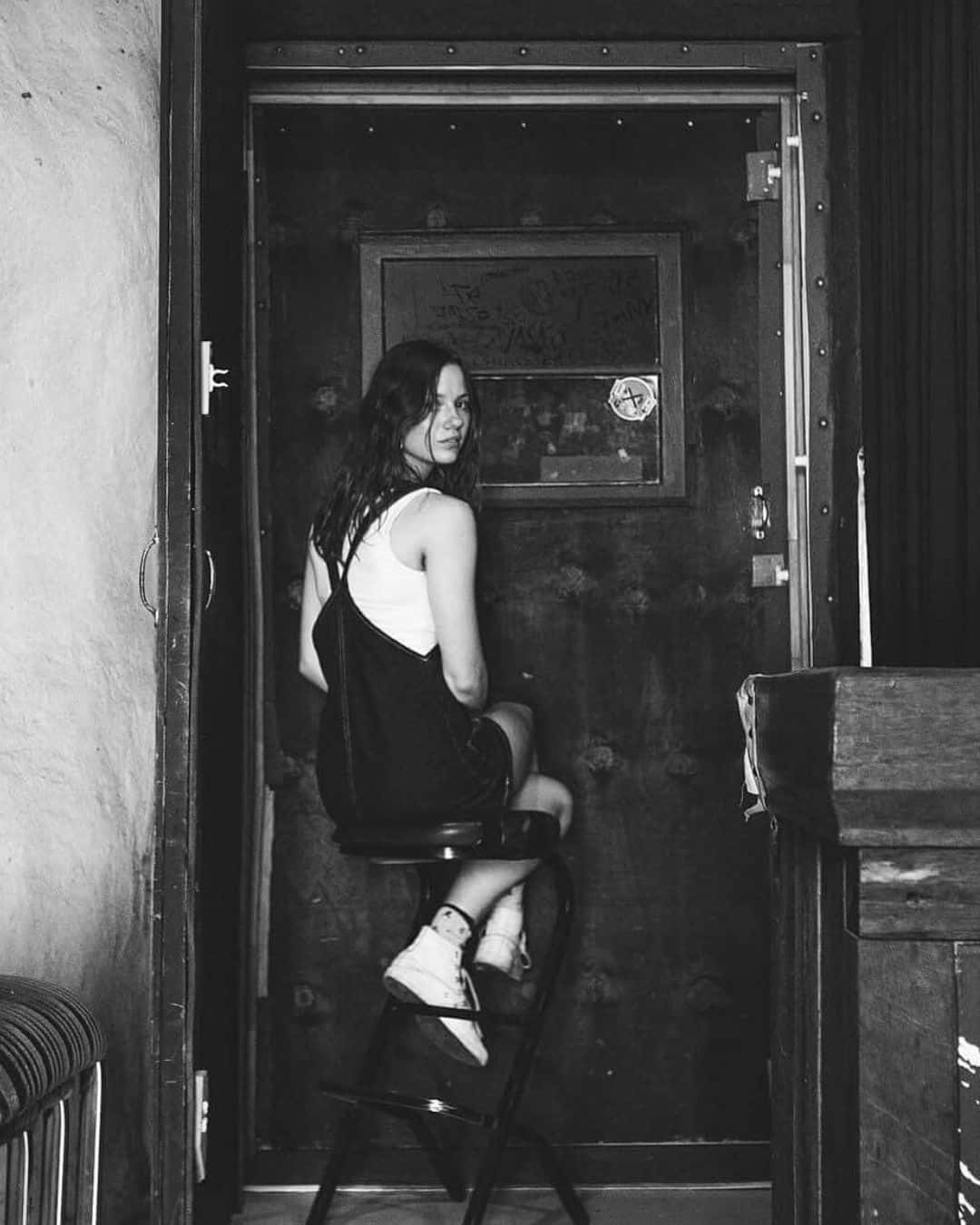 Woman Sittingon Stool Near Door Wallpaper