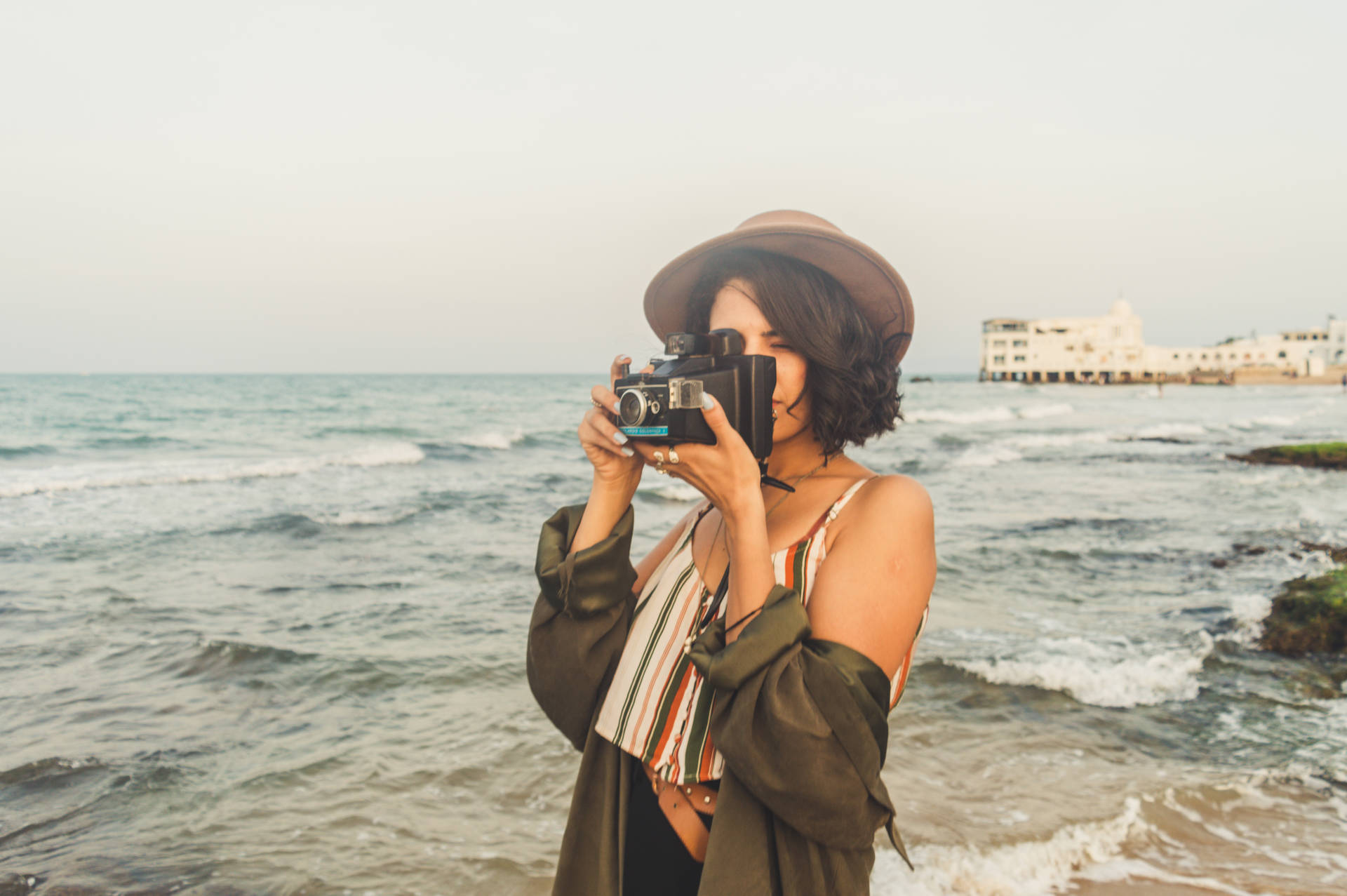 Woman holding a black camera taking a beach photo wallpaper.