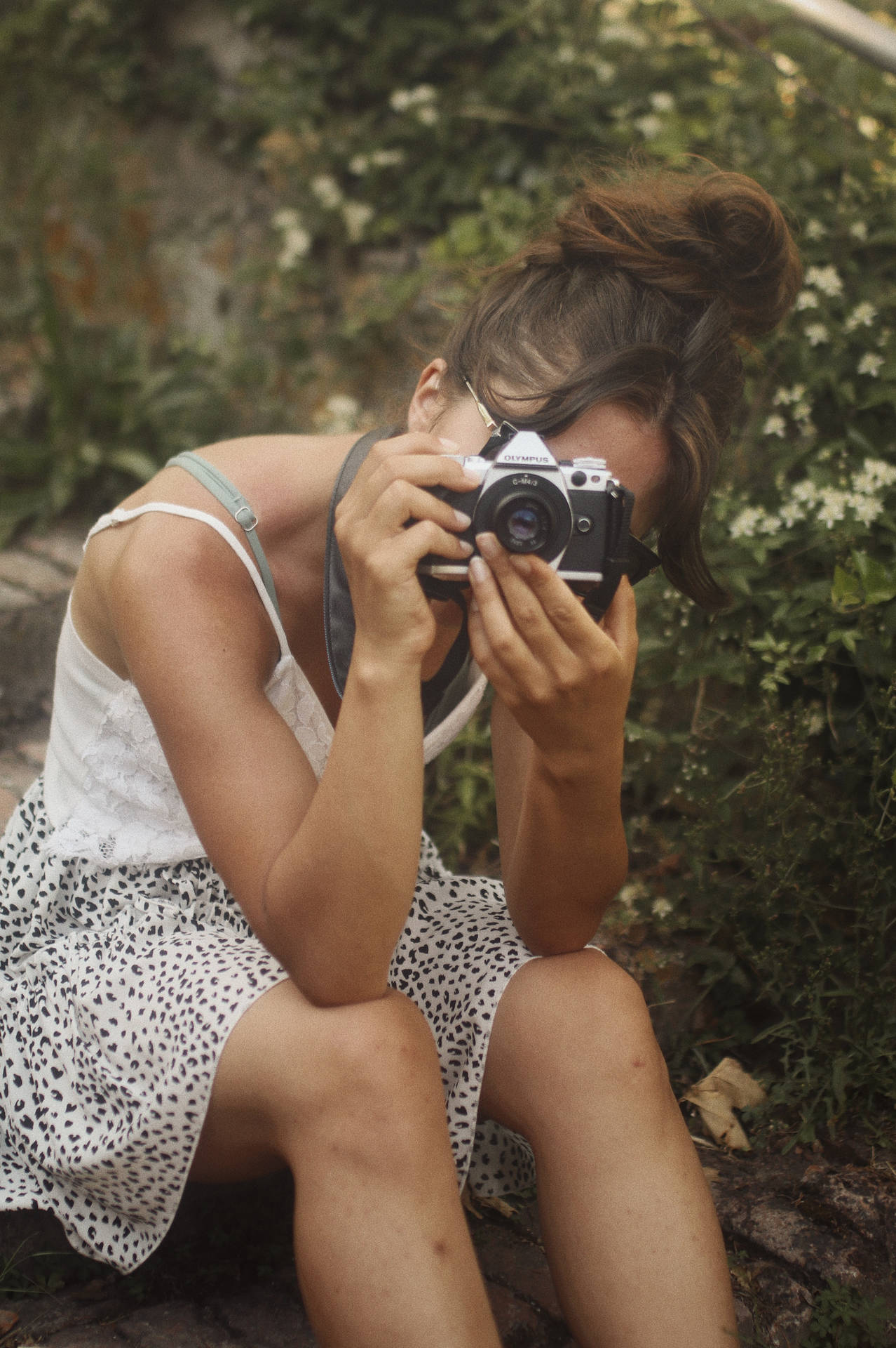 Woman holding a DSLR camera taking garden photo wallpaper.
