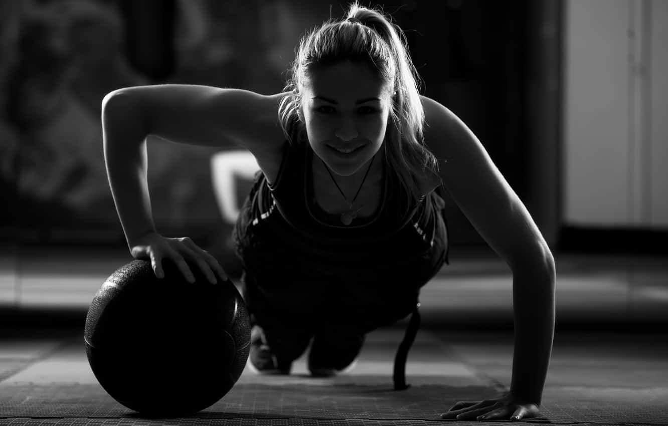 Woman Training Using An Exercise Ball Wallpaper