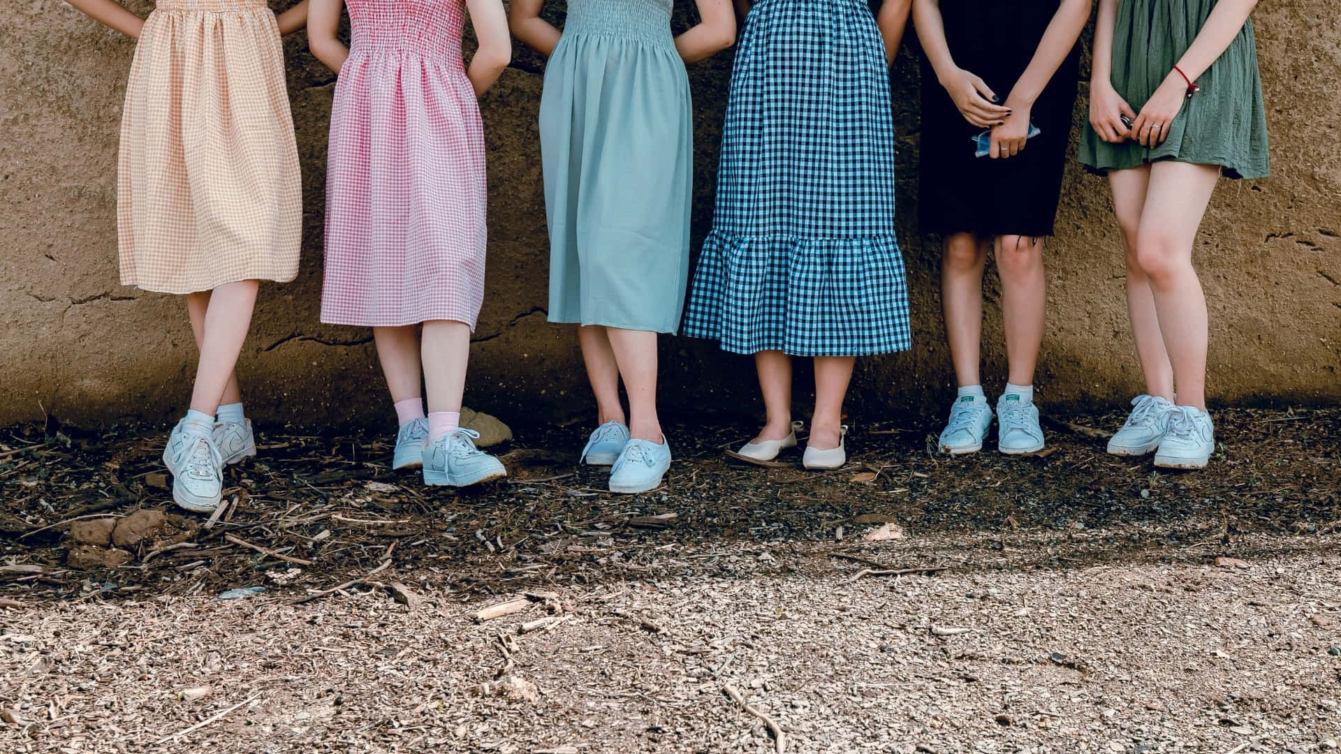 A Group Of Girls Standing In Front Of A Wall