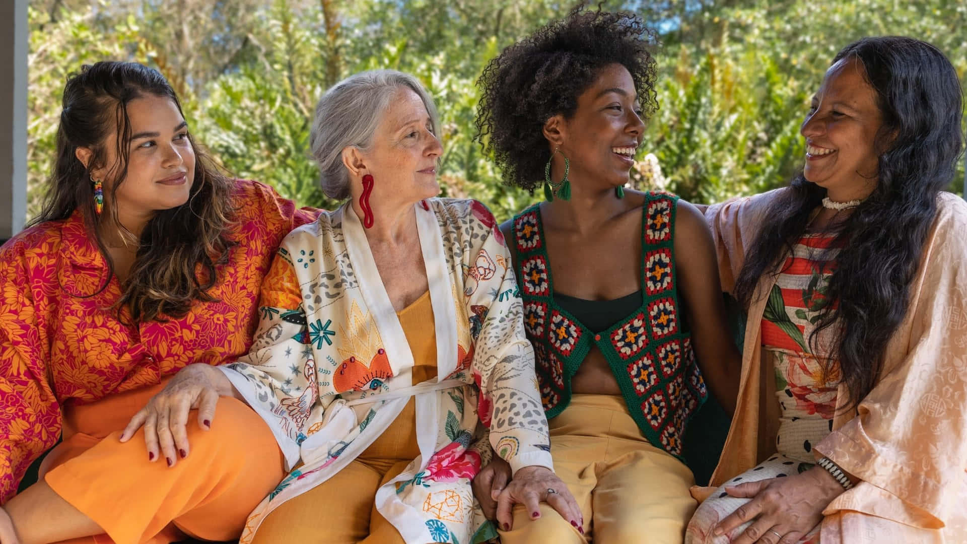 Four Women Sitting On A Bench In A Tropical Setting