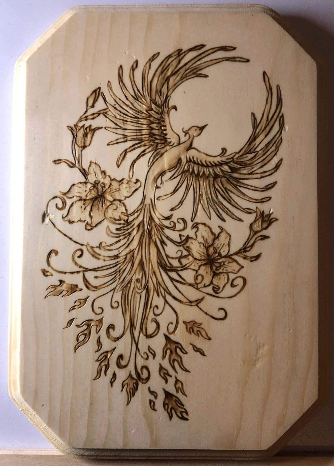 A Wooden Carving Of A Bird With Flowers