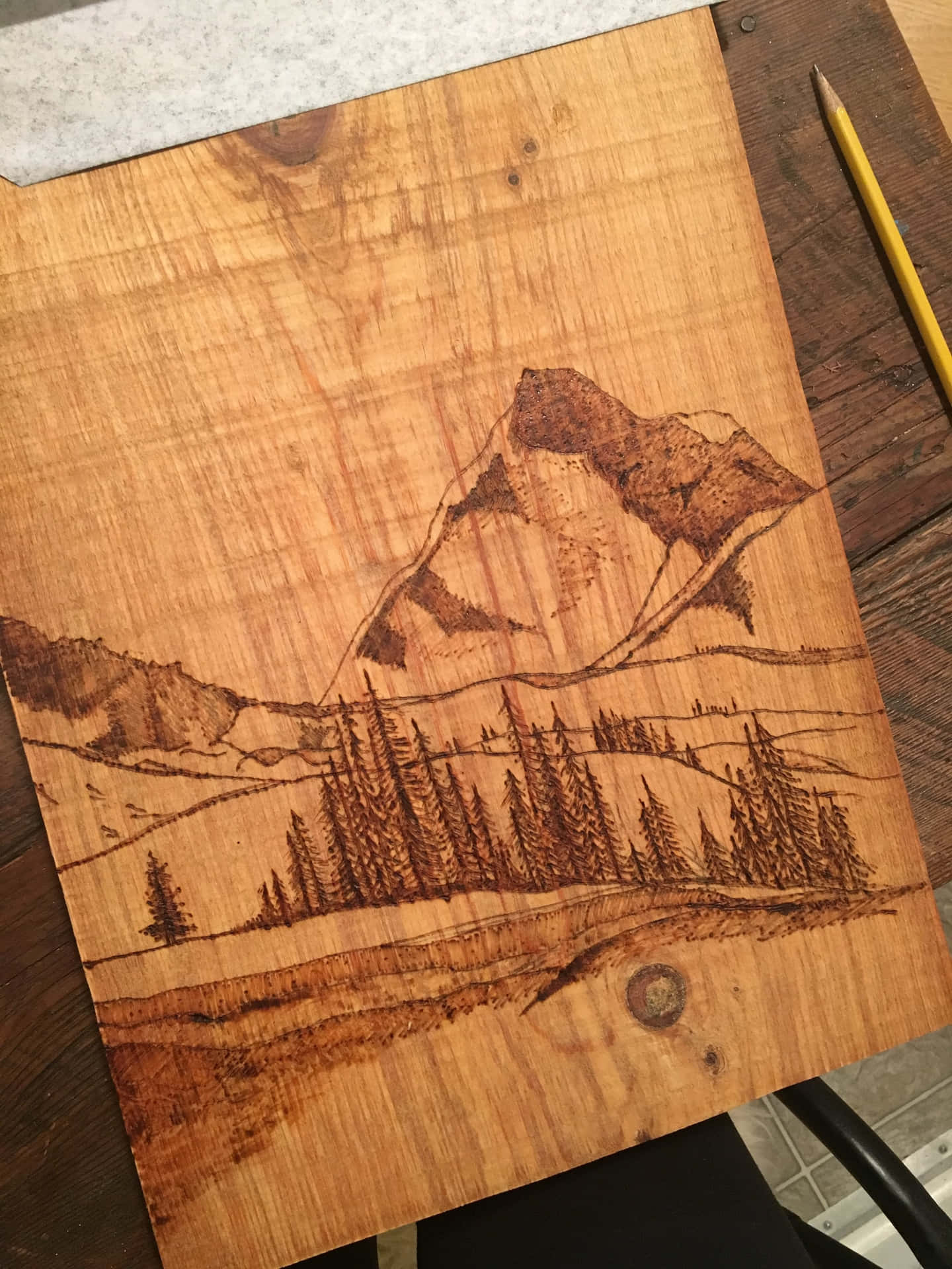 A Wooden Piece Of Art With A Mountain Scene On It