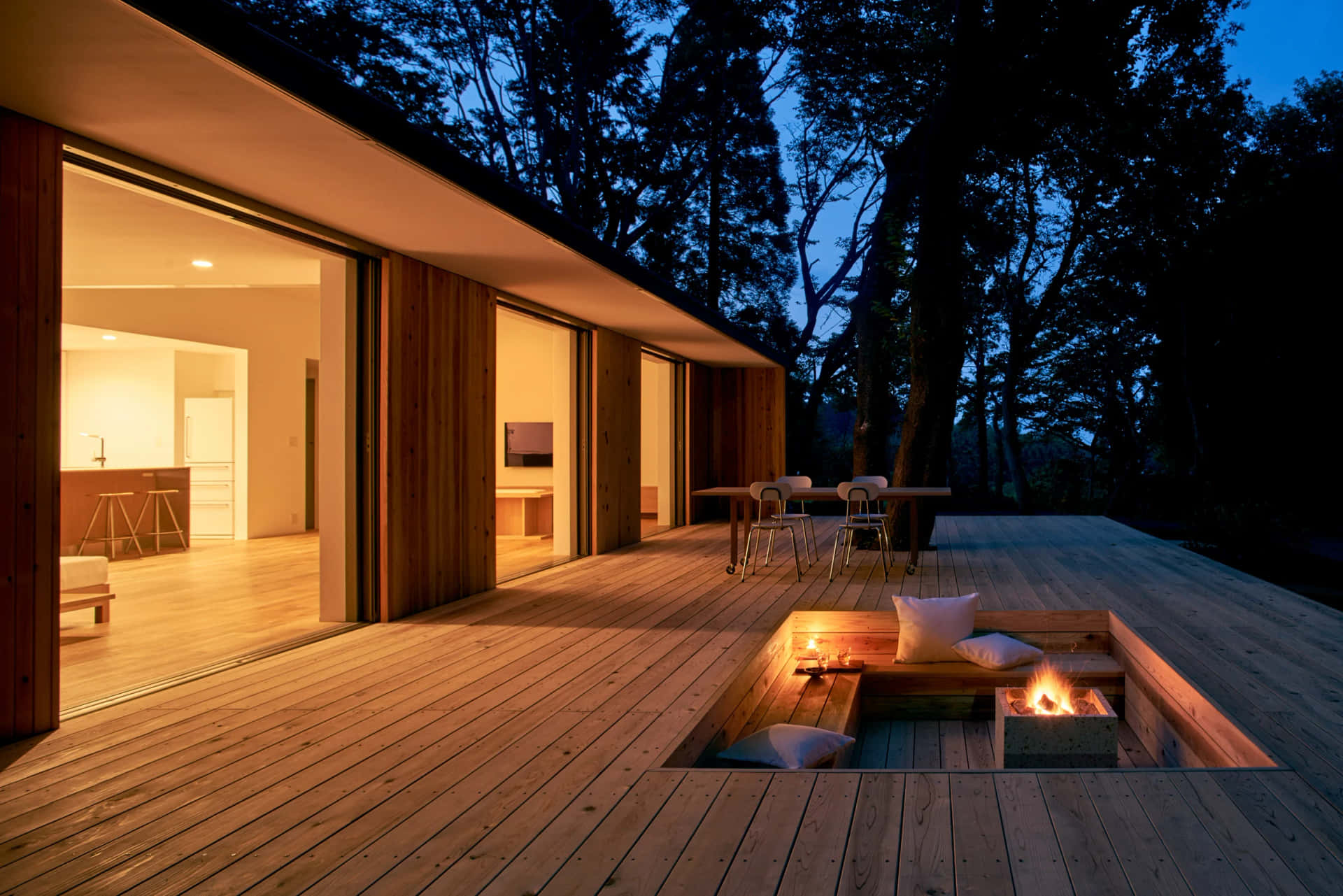 A Wooden Deck With A Fire Pit In The Evening