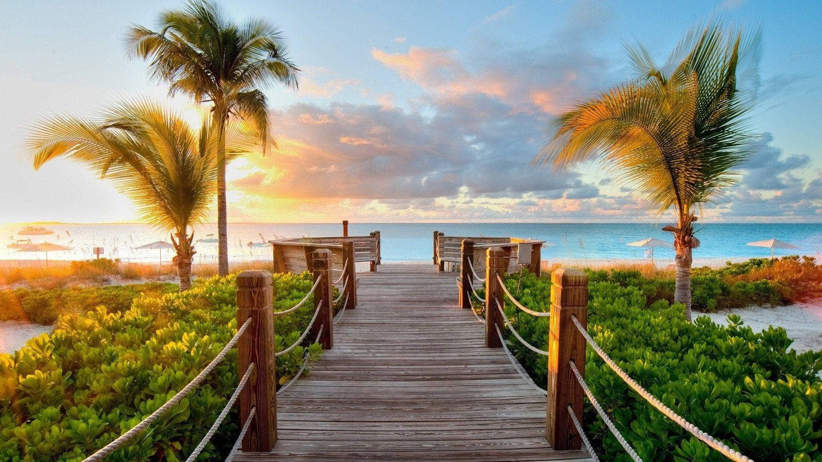 Wooden beach walkway leading up to an inviting horizon Wallpaper