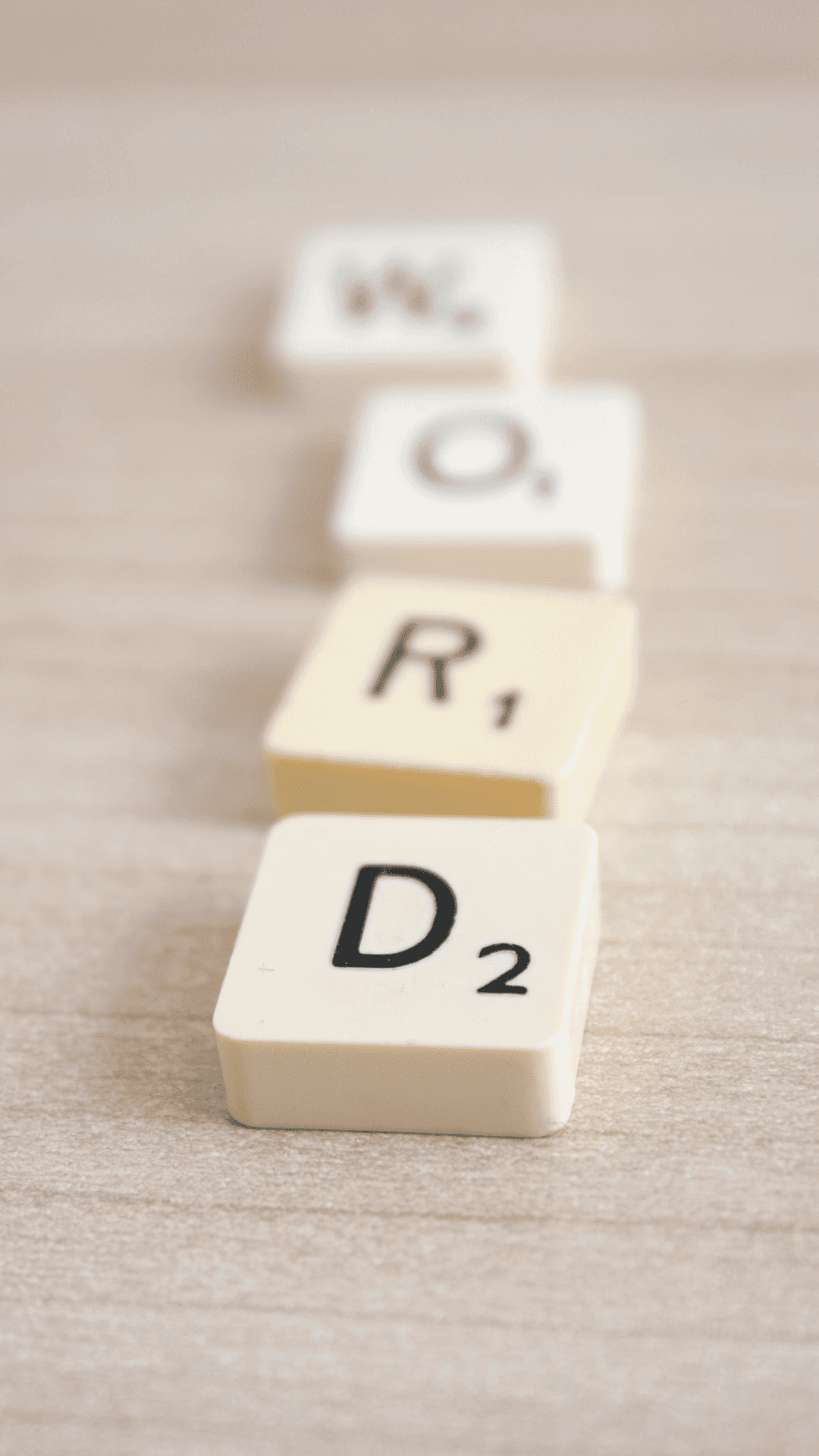 Word Background — Scribbled Scrabble tiles spelling word 'word' lie diagonally on a light wooden surface with shallow depth of field.
