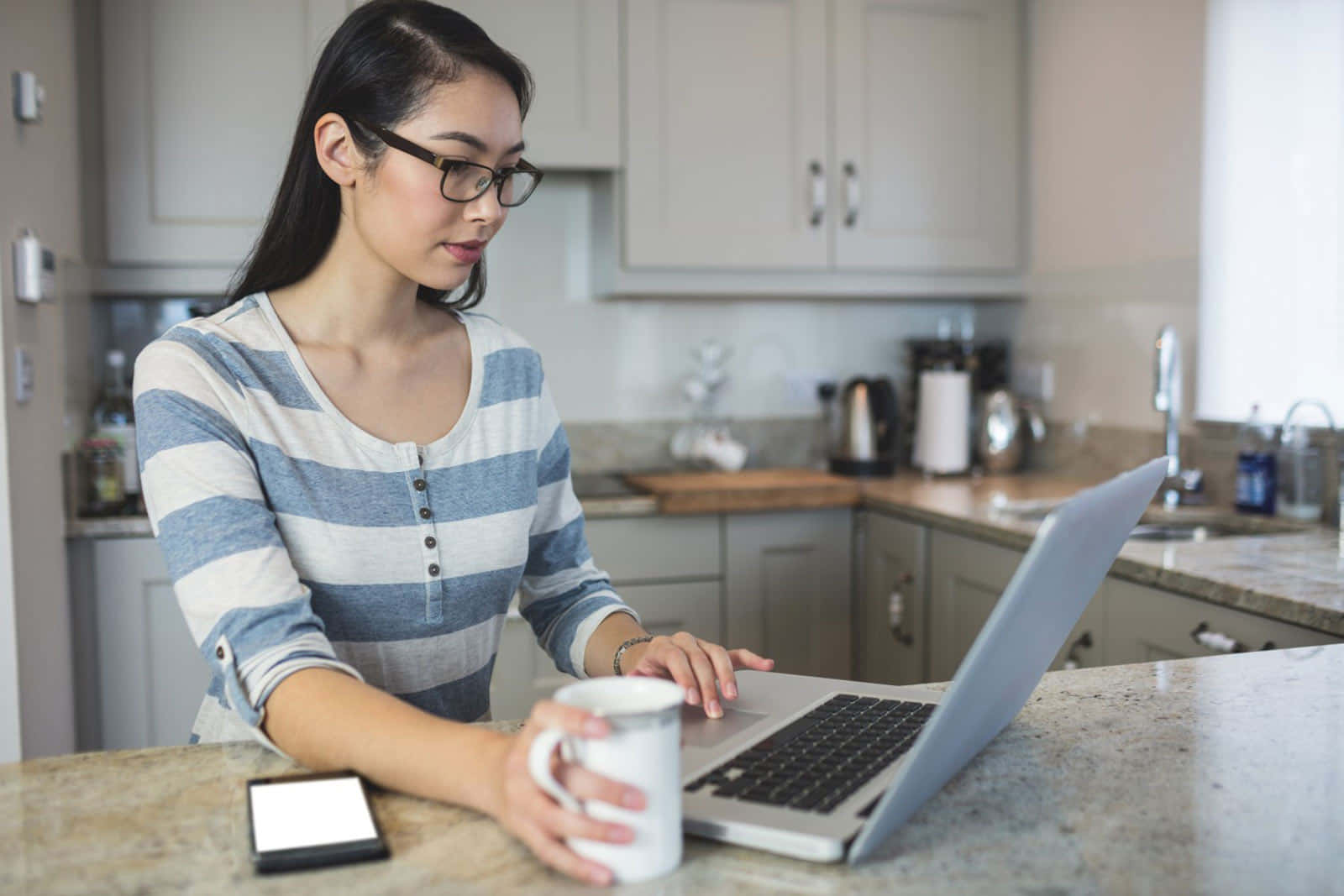 Woman Working On Laptop In Kitchen