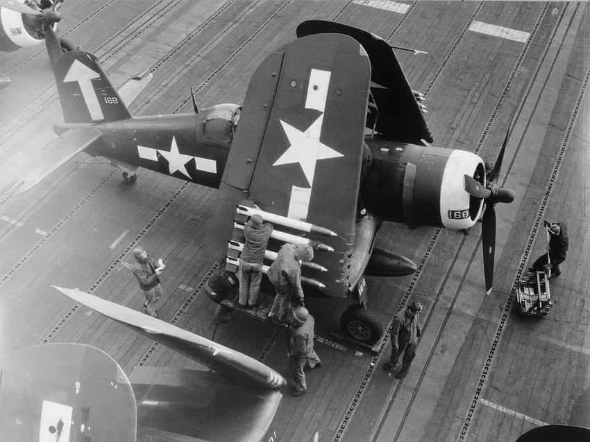 A Group Of Men Are Standing Next To A Plane On The Deck
