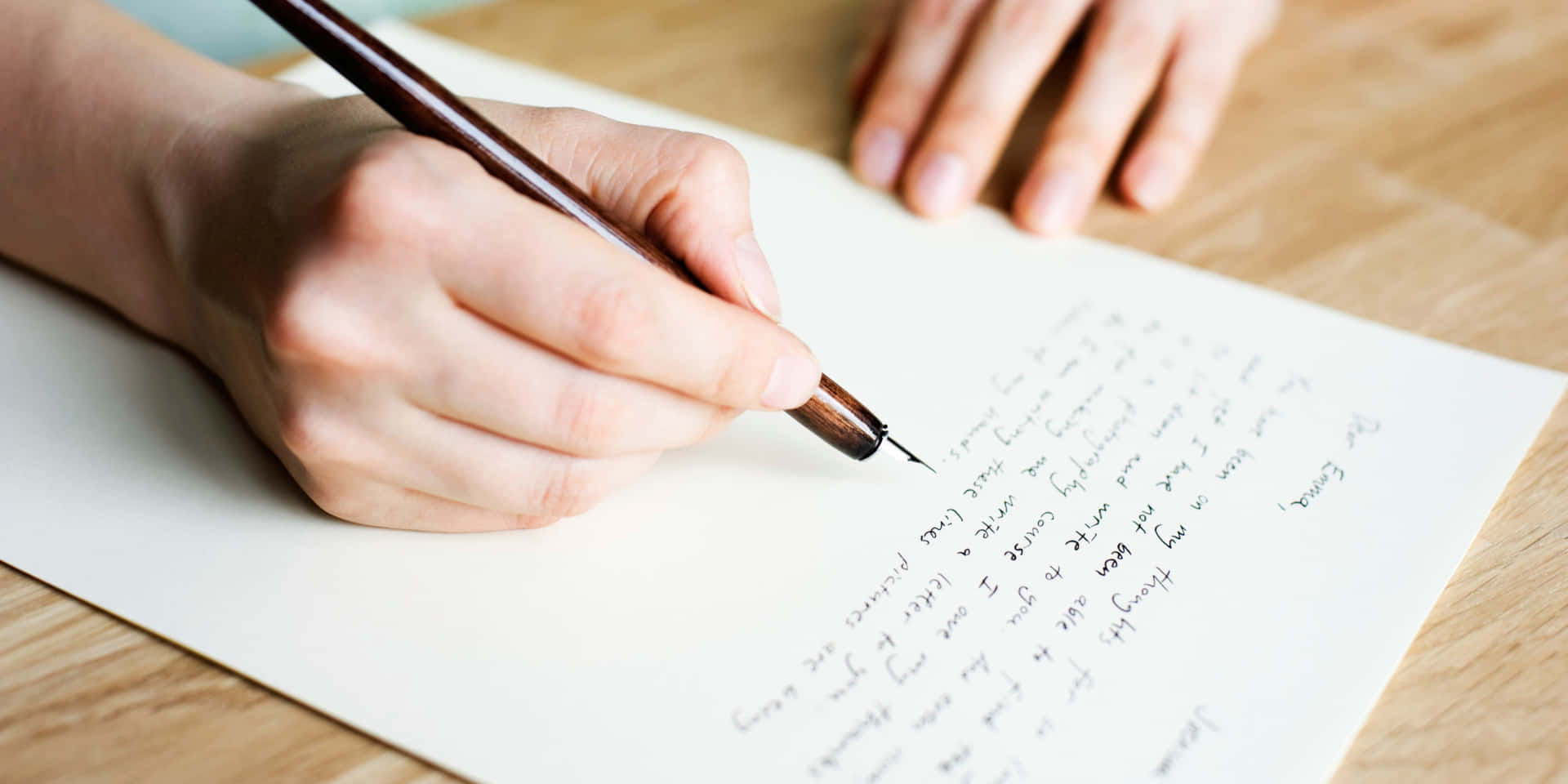 A Person Writing On A Piece Of Paper With A Pen