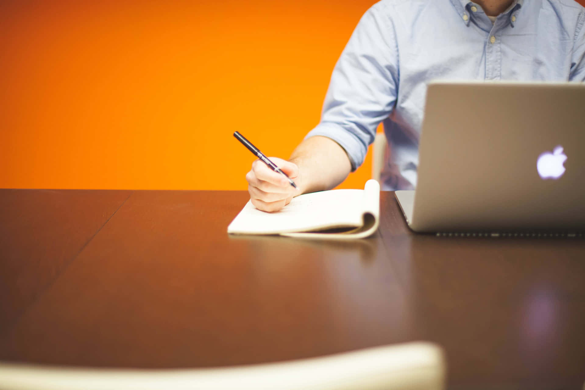 A Man Writing On A Notebook