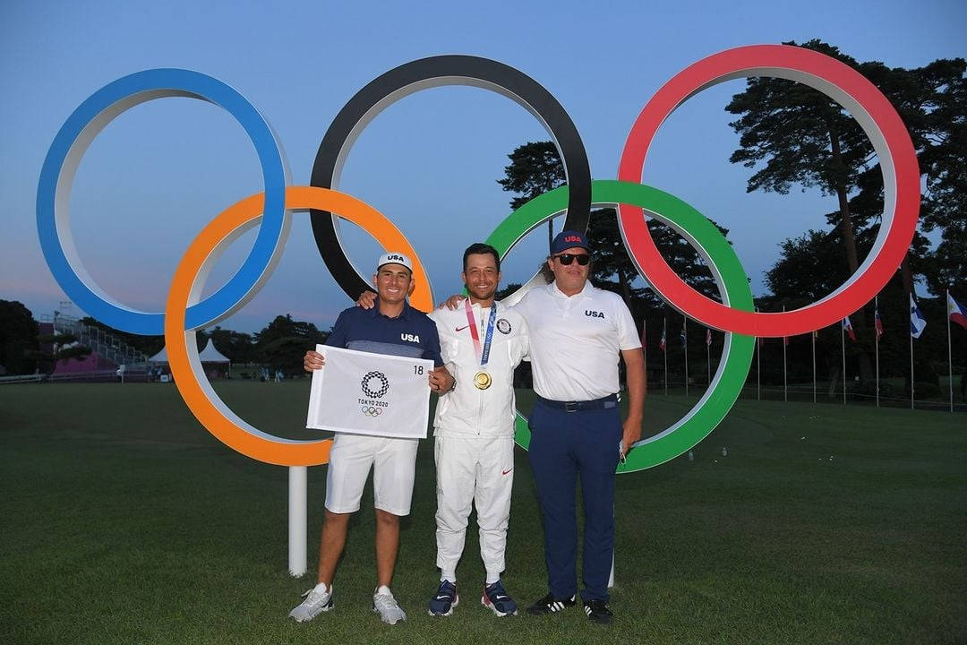 Xander Schauffele Standing Proudly with Olympics Logo in Background Wallpaper
