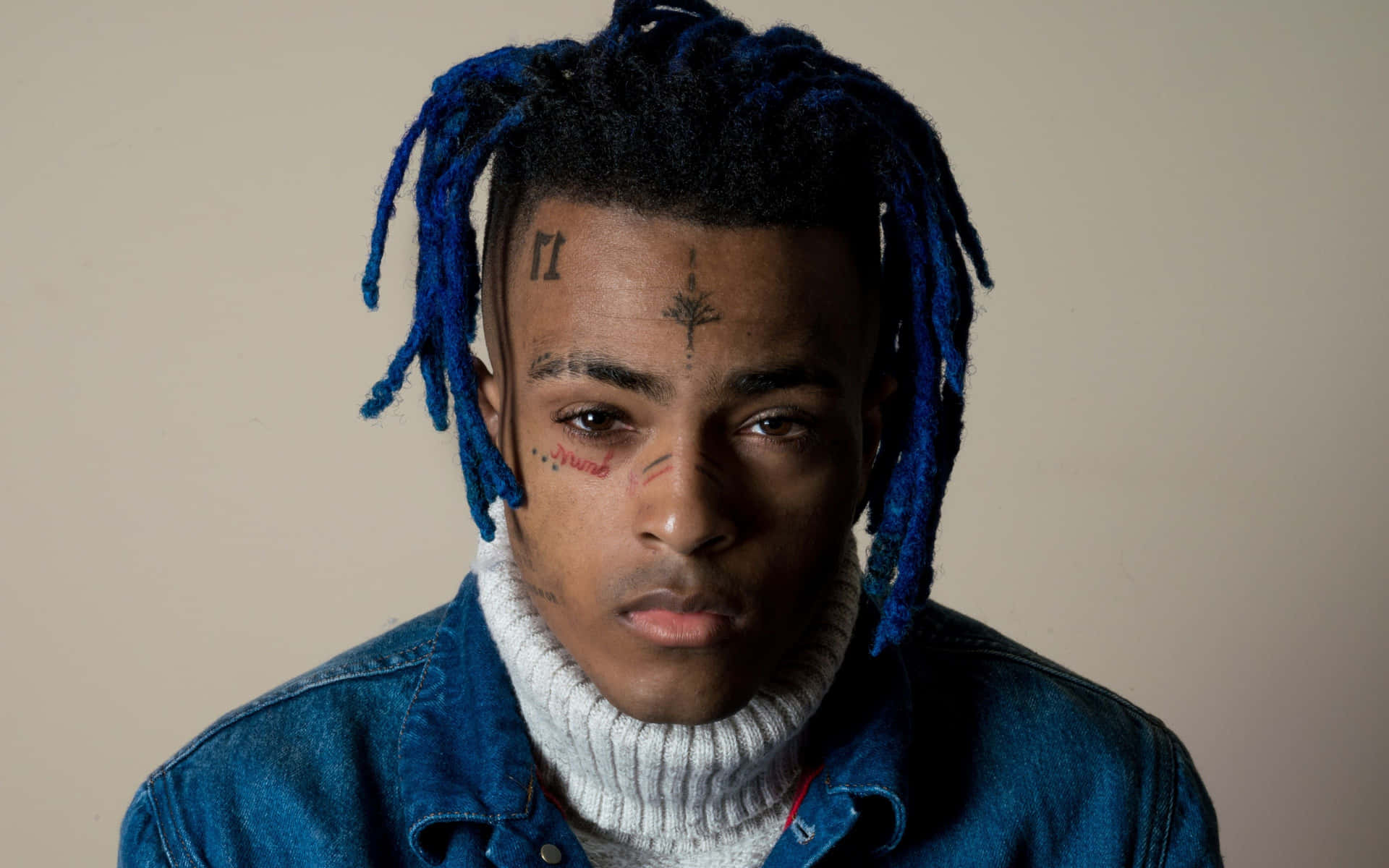 Xxxtentacion sits atop his laptop, surrounded by books and art supplies Wallpaper