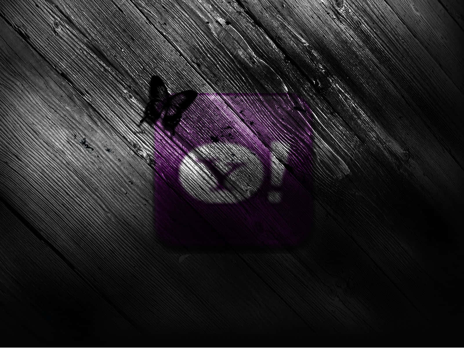 A Purple And Black Icon On A Wooden Background
