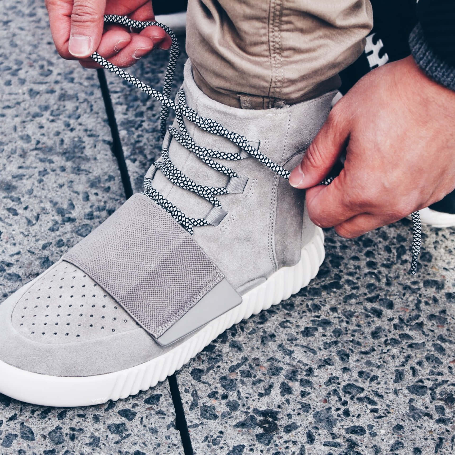En person binder snørebånd på et grå sneaker. Wallpaper