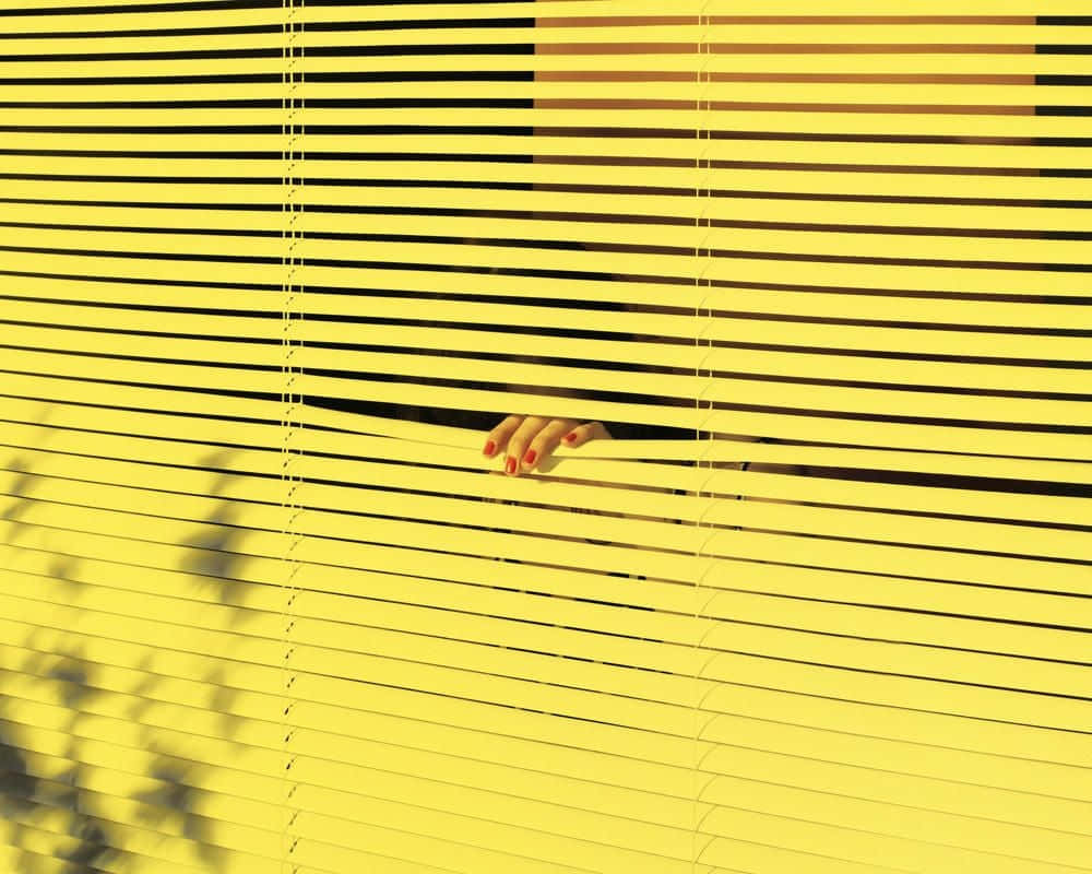 Hand Coming Out From Blinds Yellow Background