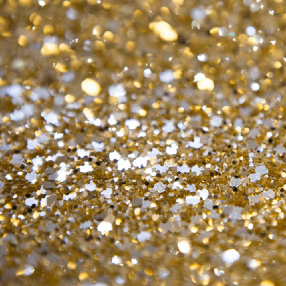 A Close Up Of Gold Glitter On A Table