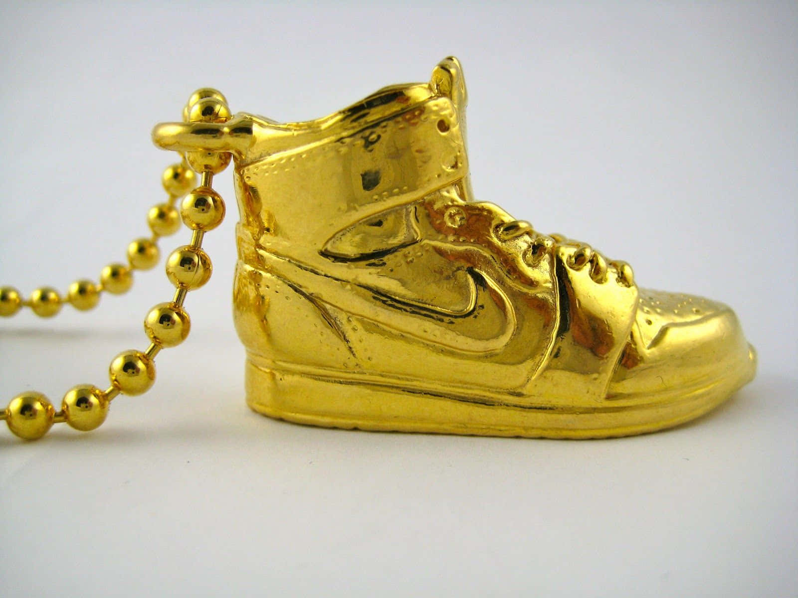 Et guld Nike sko med en kæde på det. Wallpaper