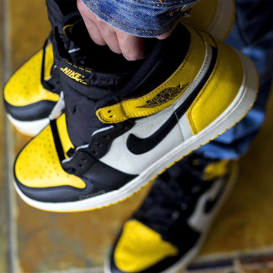 En person, der holder et par gule og sorte Air Jordan 1s Wallpaper