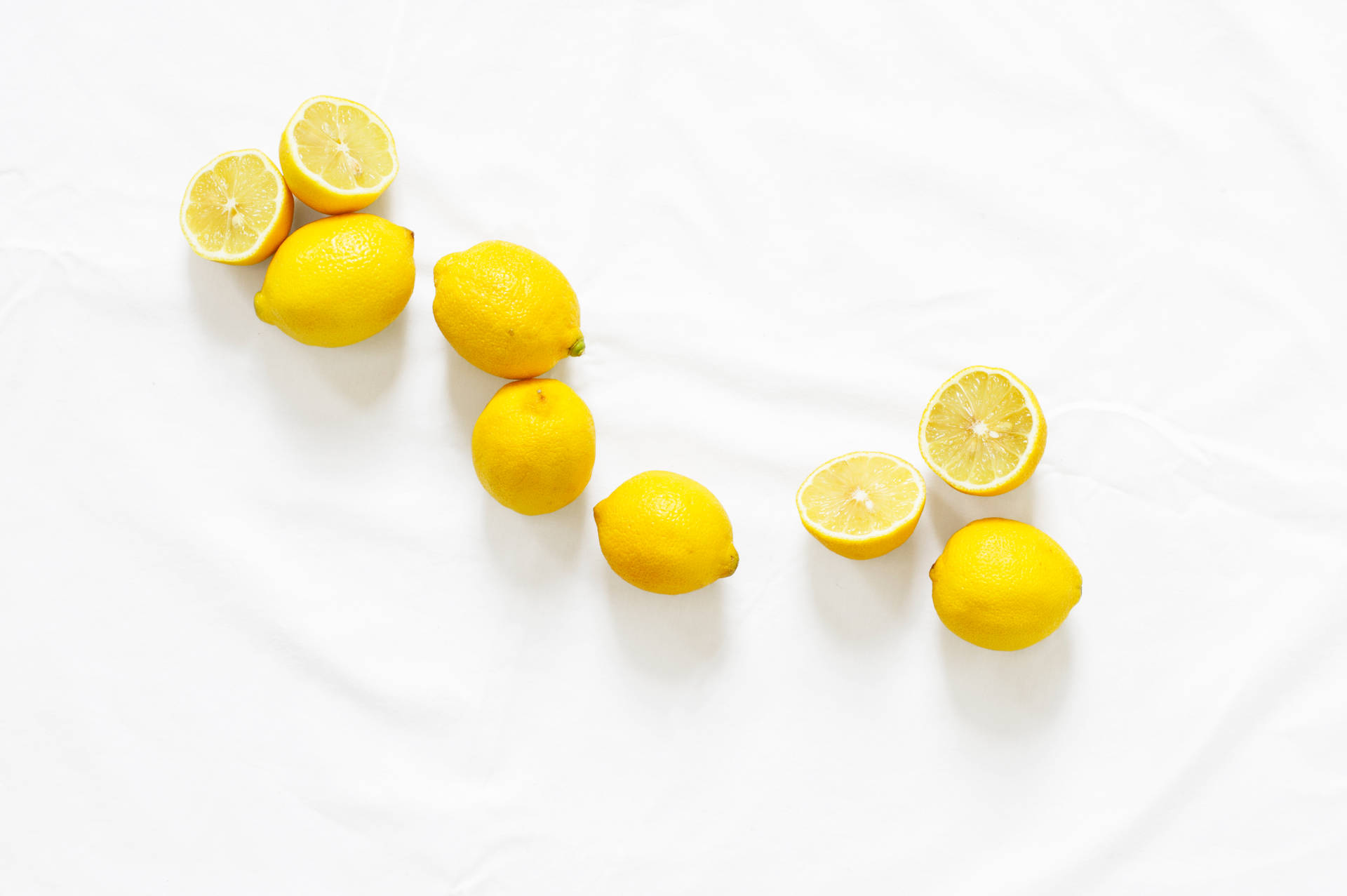 Yellow zesty American lemons on white surface wallpaper.