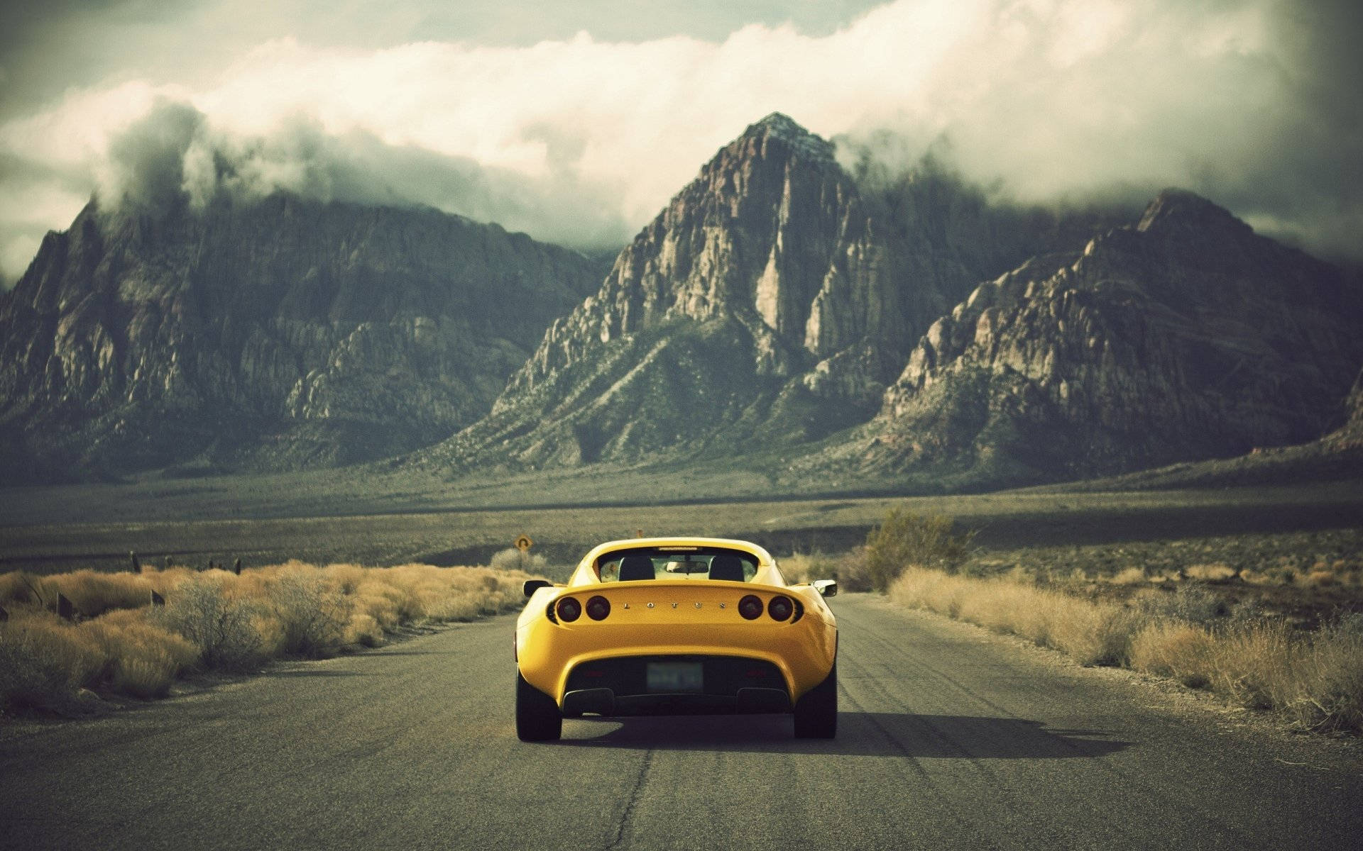 Effortless Power - Yellow Lotus Car Cruising through the Arid Desert Wallpaper