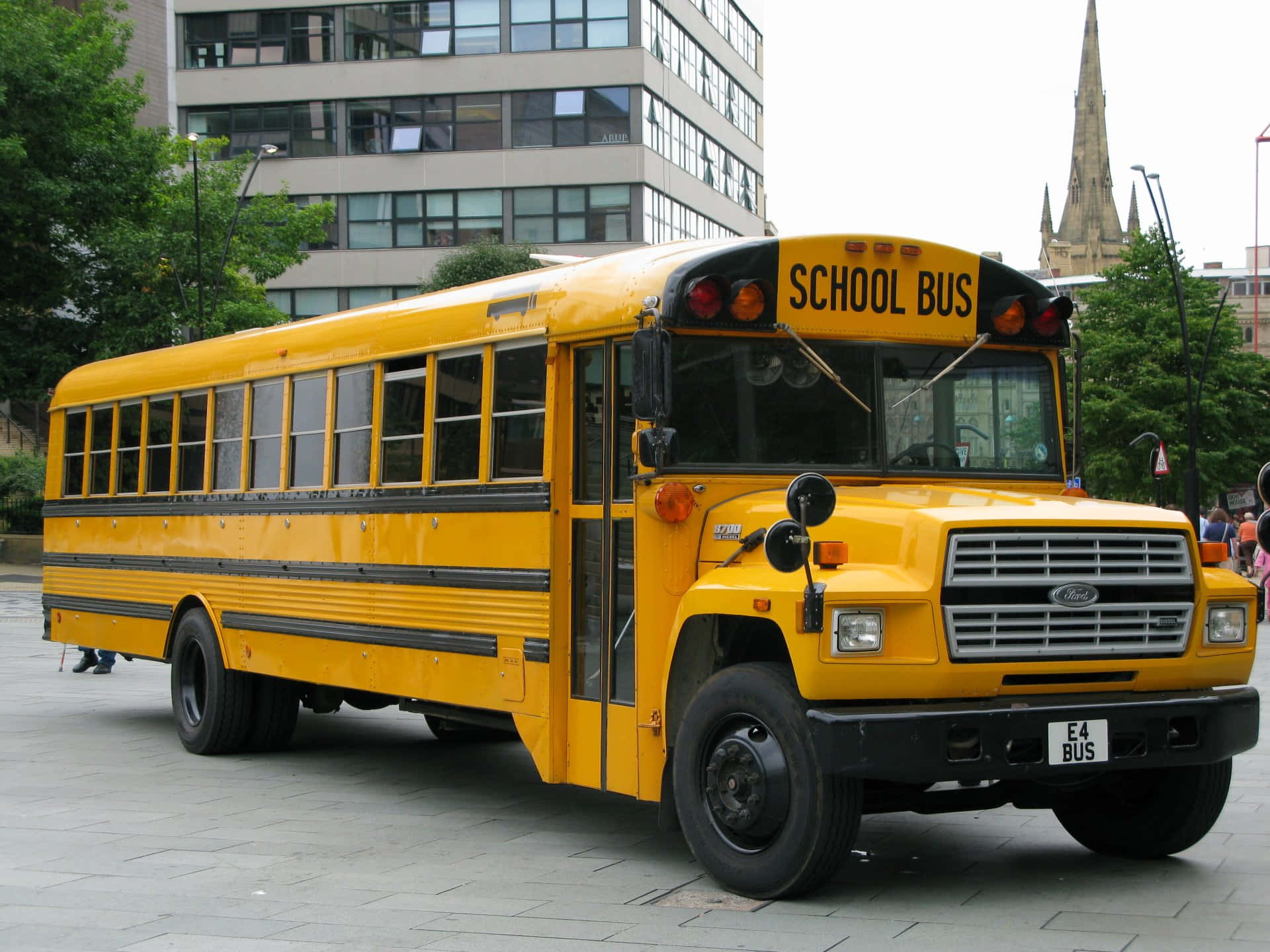 A classic yellow school bus parked on a sunny day Wallpaper