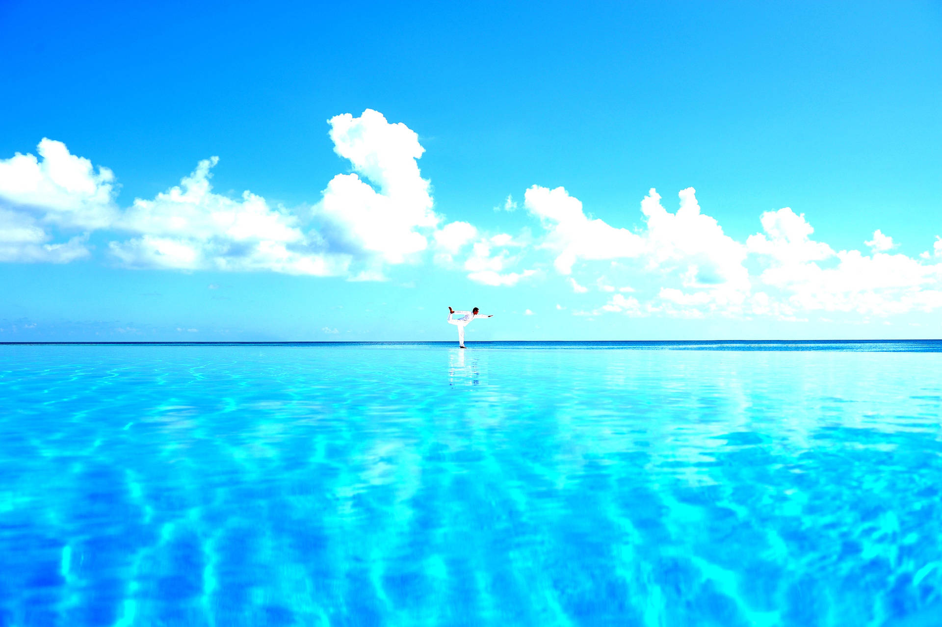 Finding Serenity: A Tranquil Yoga Pose Above Sparkling Blue Water Wallpaper