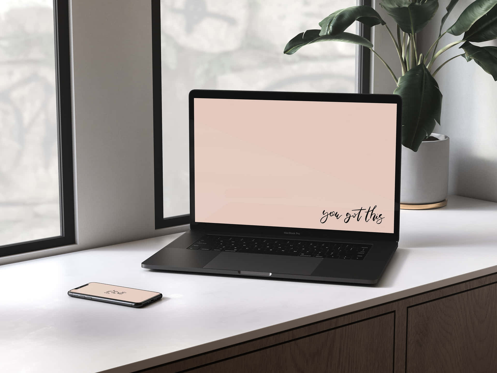 Et laptop og telefon på et skrivebord ved siden af et vindue. Wallpaper