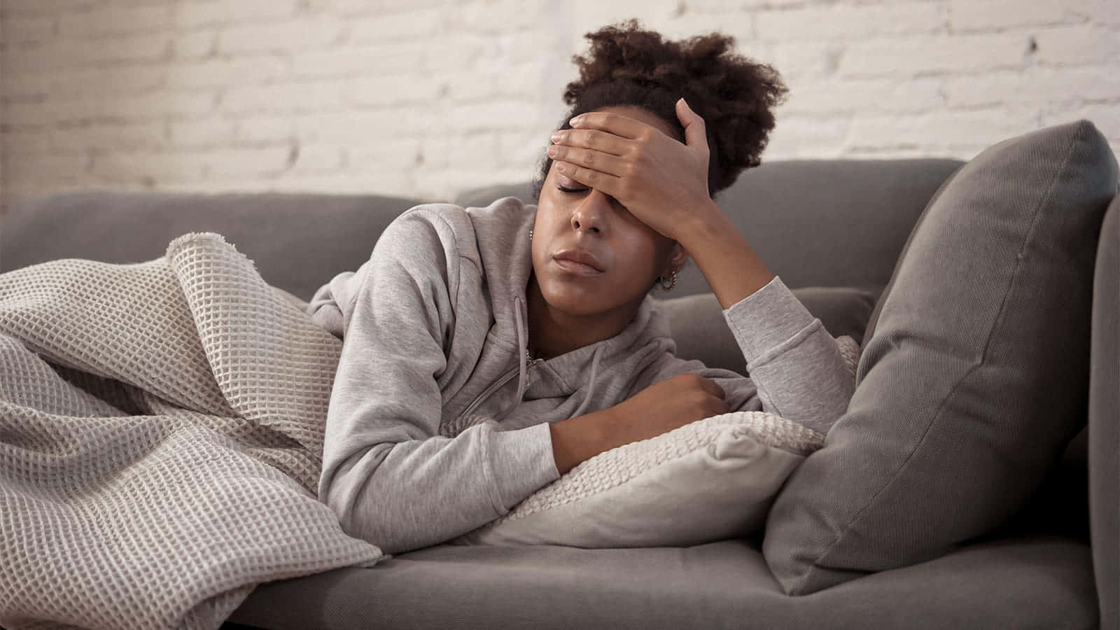 Unge sorte kvinde med feber på sofaen Wallpaper