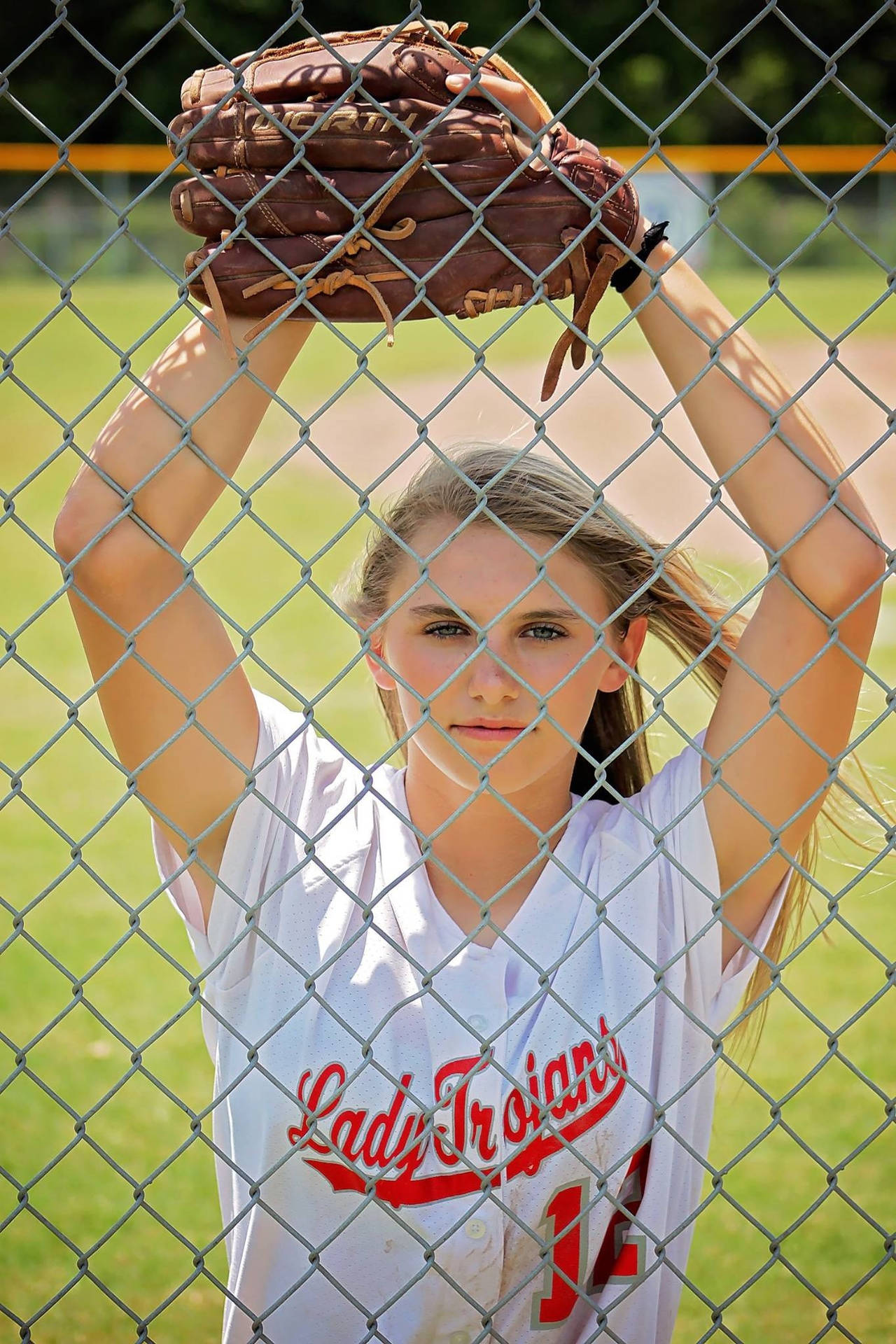 Young Girl Fiercely Pitching In A Softball Game Wallpaper