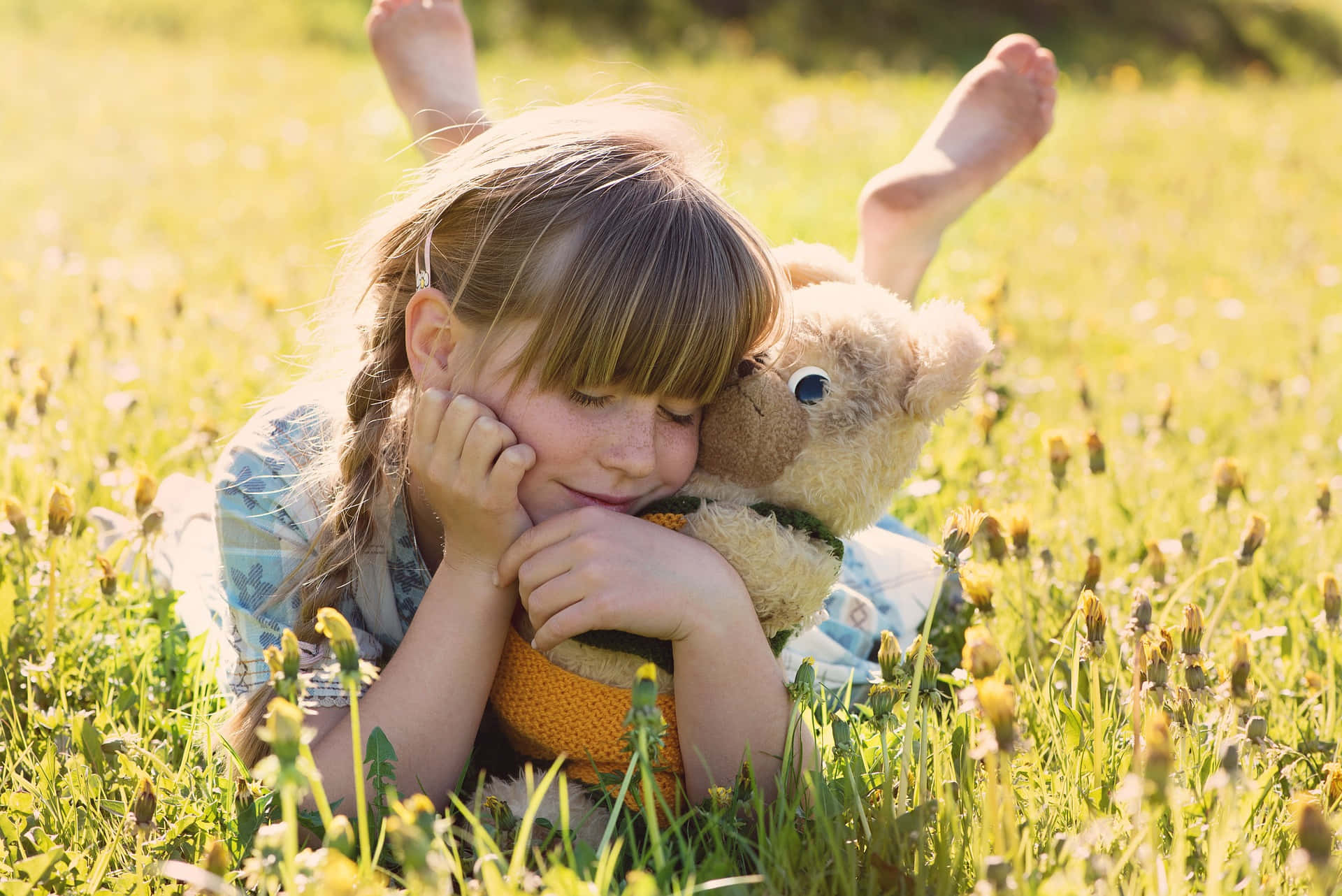 Young Girl Lying On A Flower Field Hugging Her Tangible Teddy Bear Wallpaper