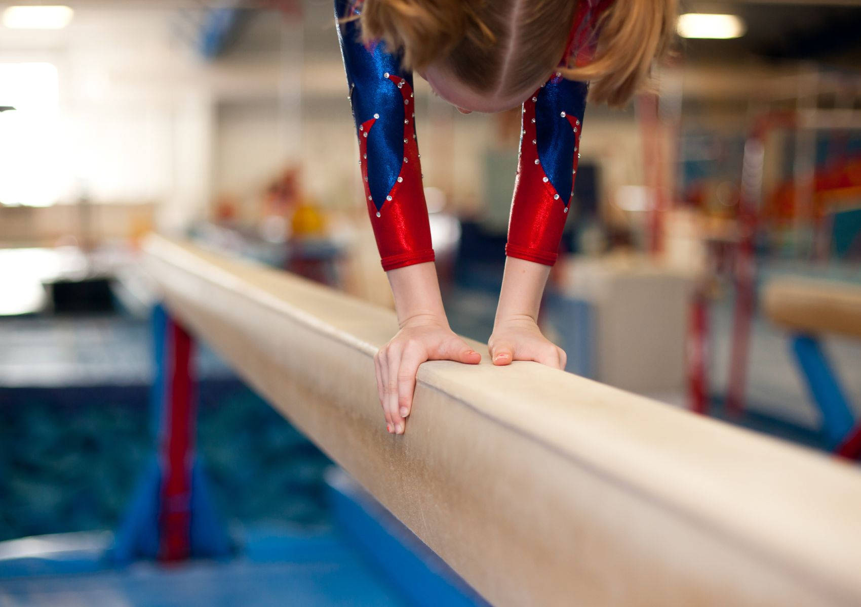 Young Gymnast Doing Handstand On Balance Beam Wallpaper