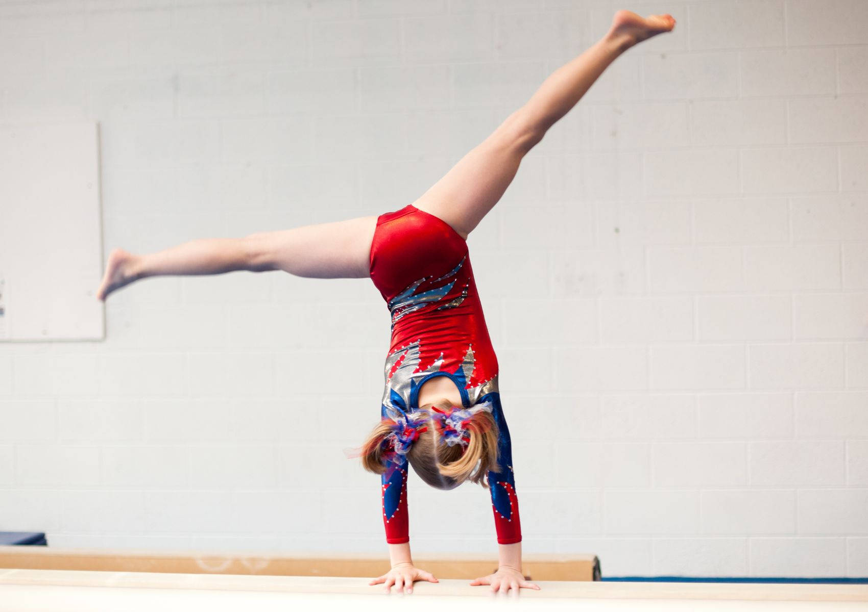 Young Gymnast Performs Cartwheel On Balance Beam Wallpaper